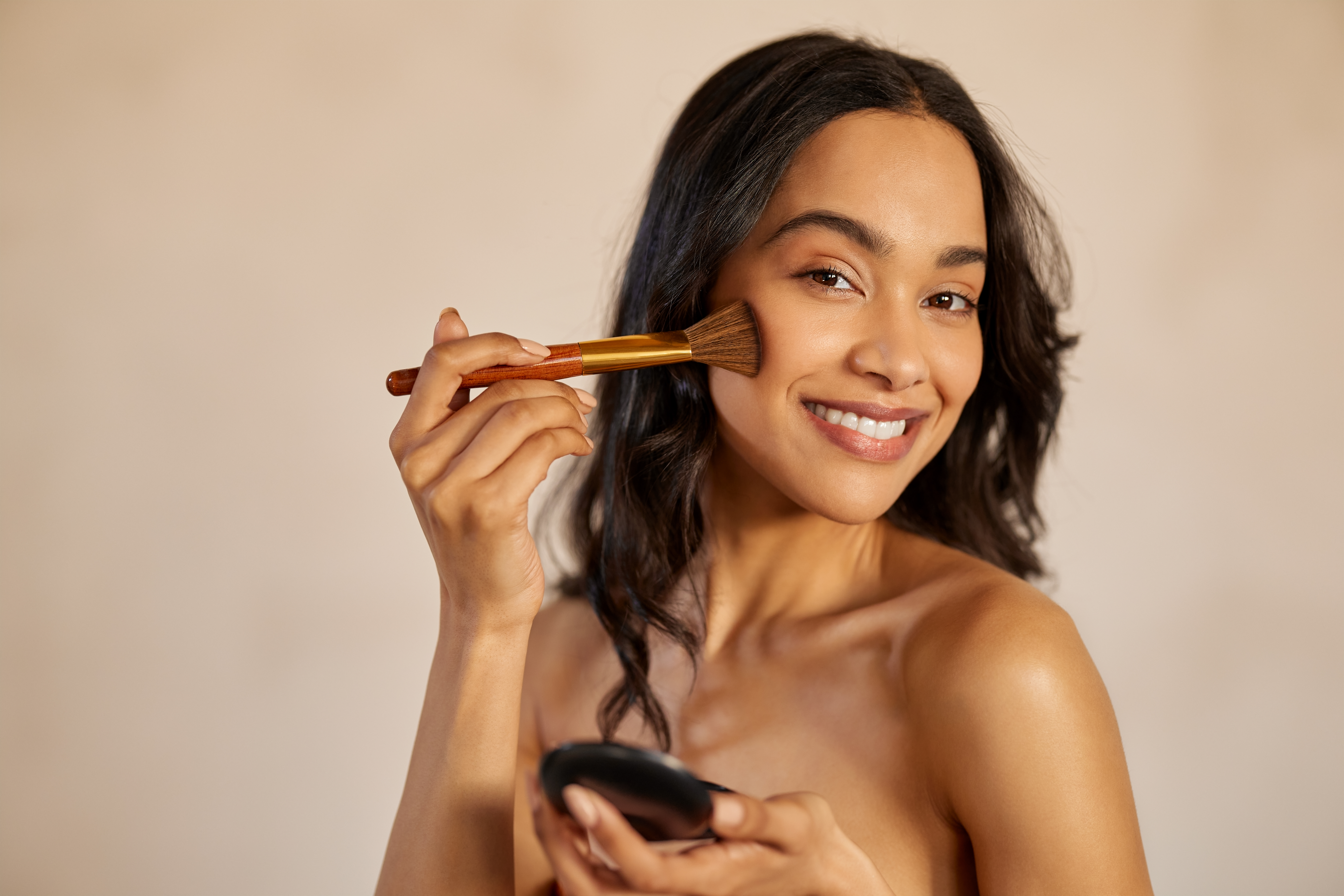 Happy latin beauty woman applying makeup powder