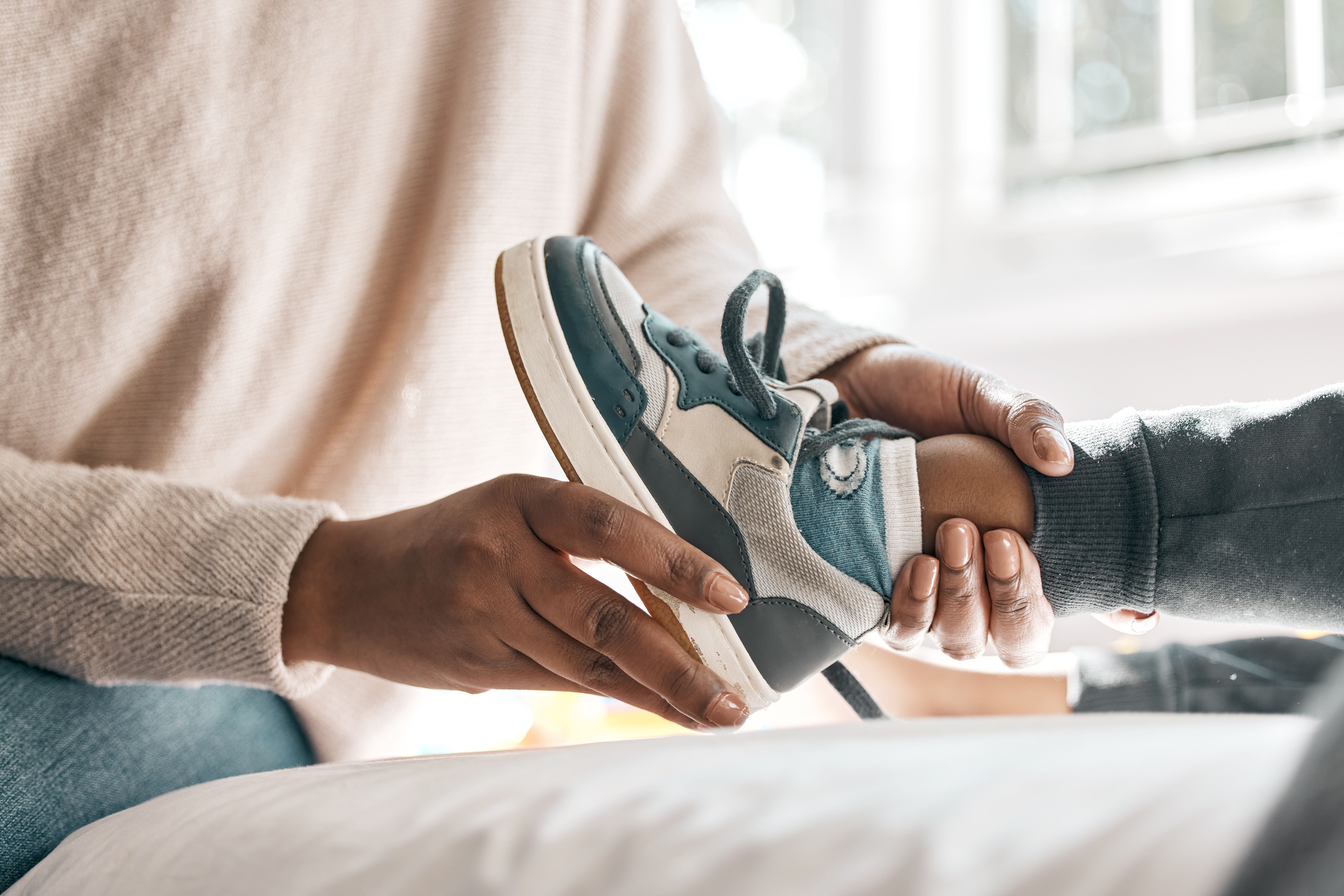 Cropped shot of an unrecognizable helping her son with his shoes while sitting on a bed at home