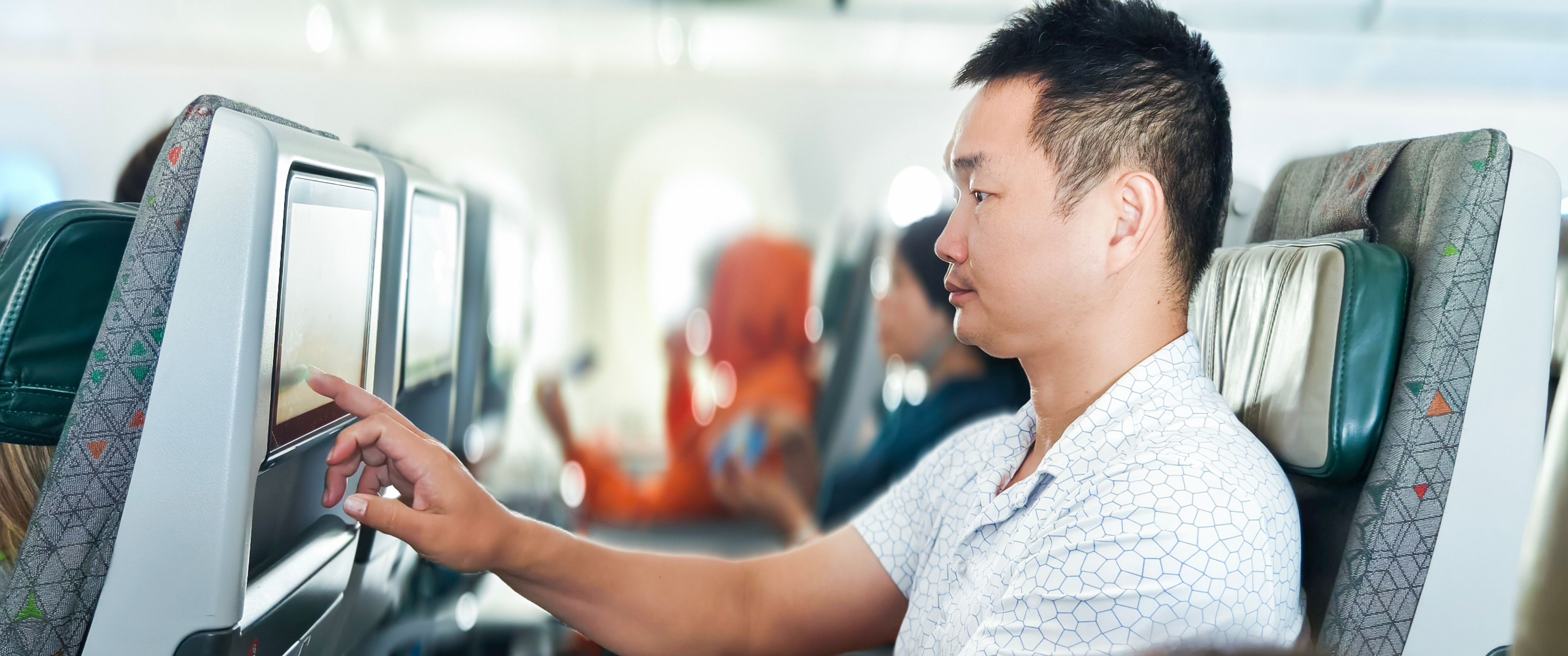 A middle-aged Asian man watches TV on the plane. A middle-aged Asian man watches TV on the plane.