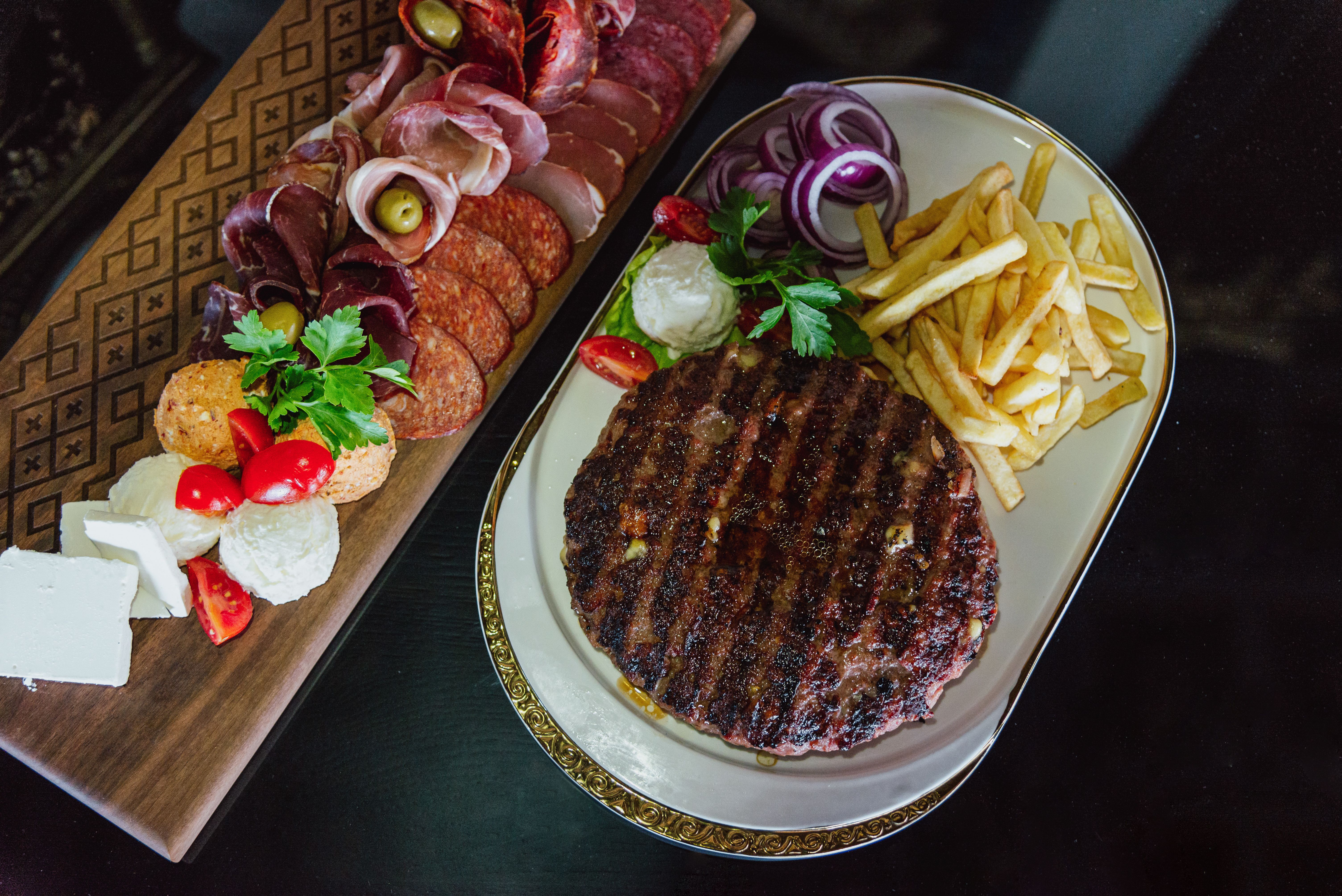Grilled balkan meat pljeskavica with french fries and traditional salami, cheese and specialties, stock photo