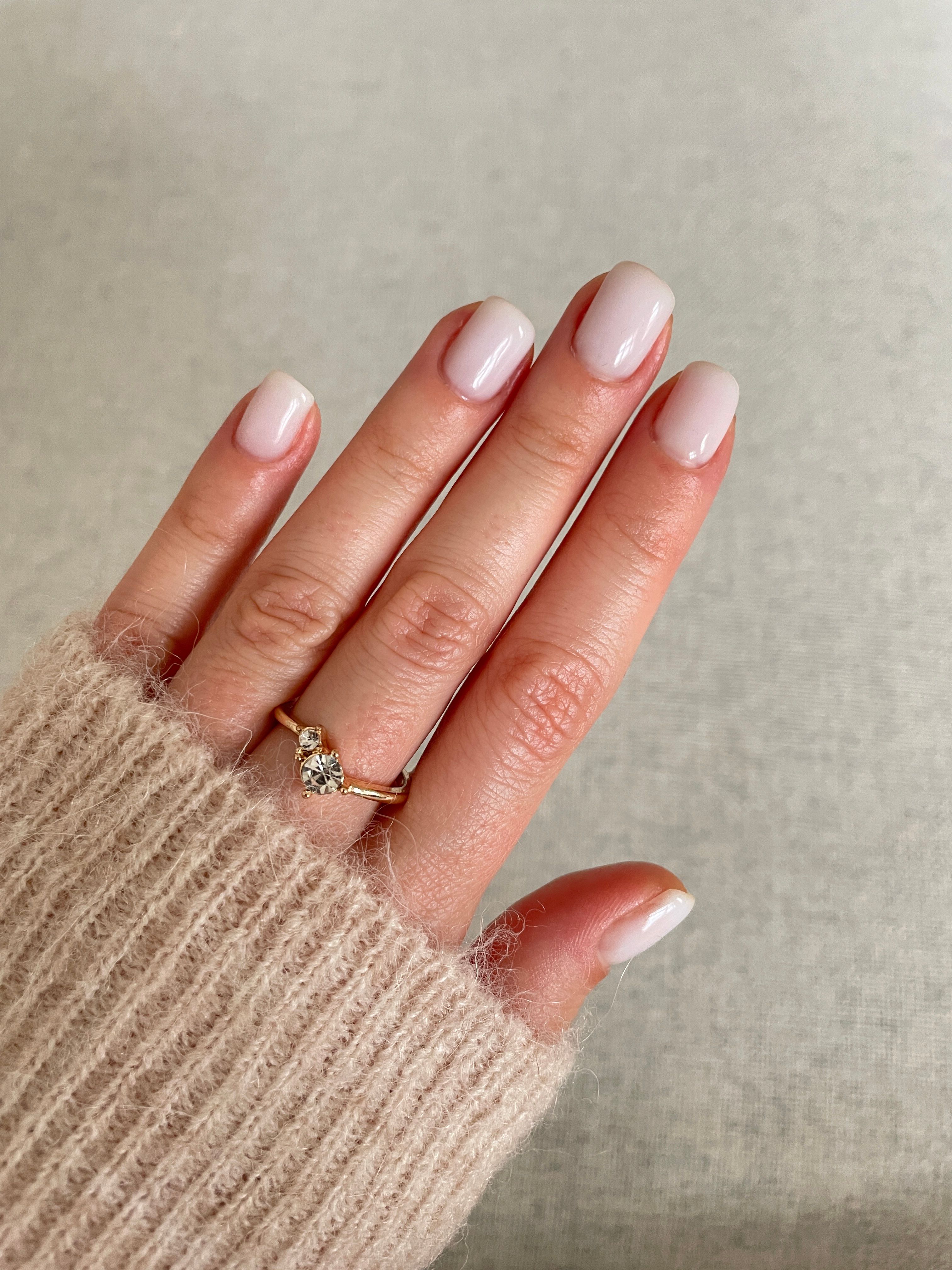 Woman showing her white neutral manicure and gold ring Woman showing her white neutral manicure and gold ring