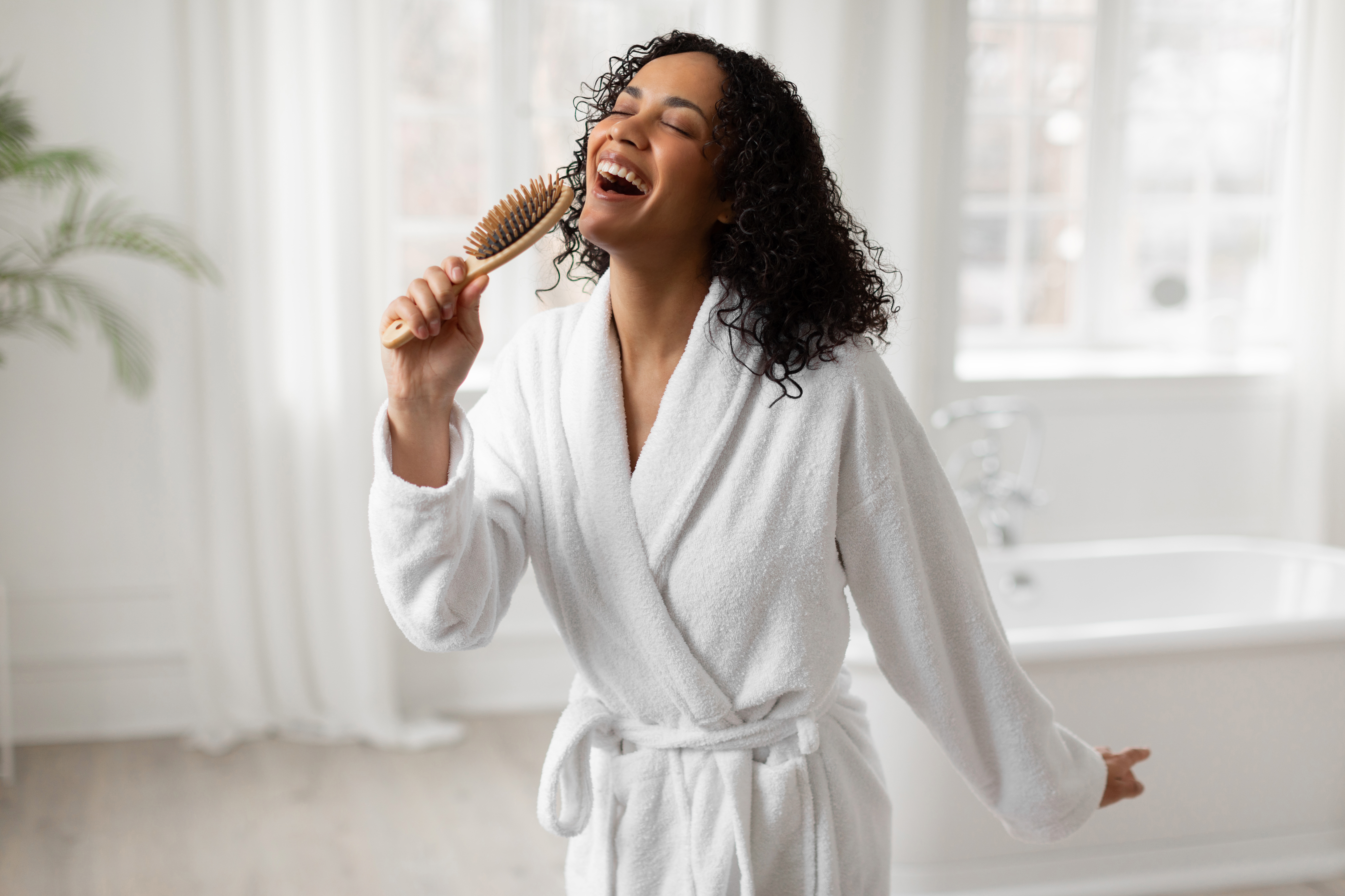 Excited black lady singing holding hairbrush and having fun in light bathroom interior, enjoy haircare and morning beauty routine Excited black lady singing holding hairbrush and having fun in light bathroom interior, enjoy haircare and morning beauty routine