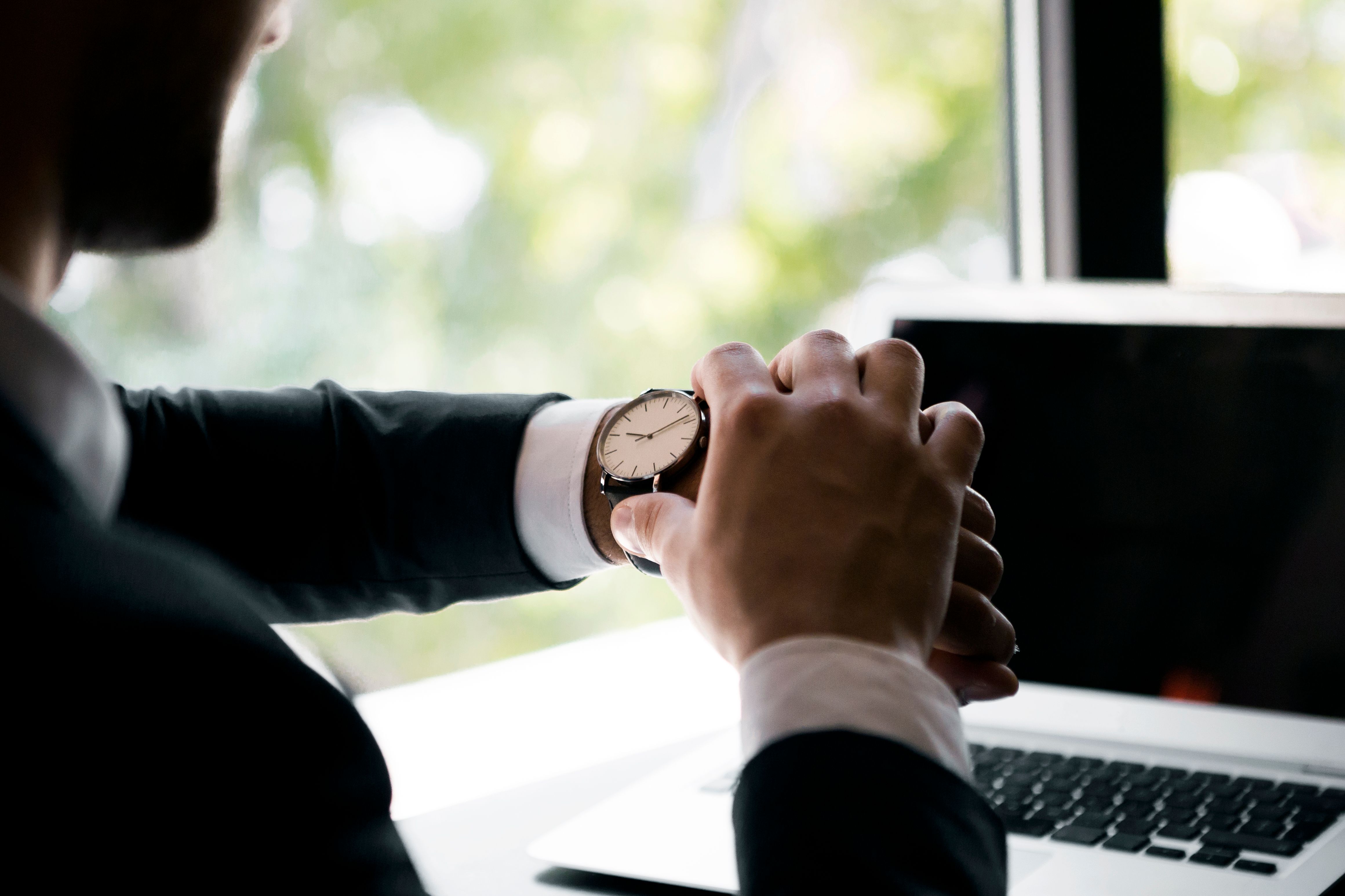 Male manager holding and looking watch in office Male manager holding and looking watch in office