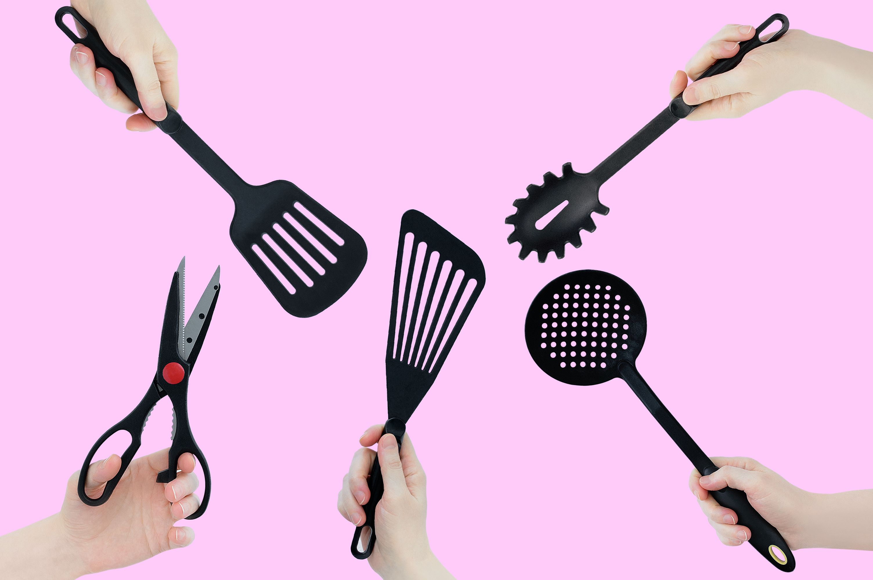 Black kitchen utensils in hands. Pink background.