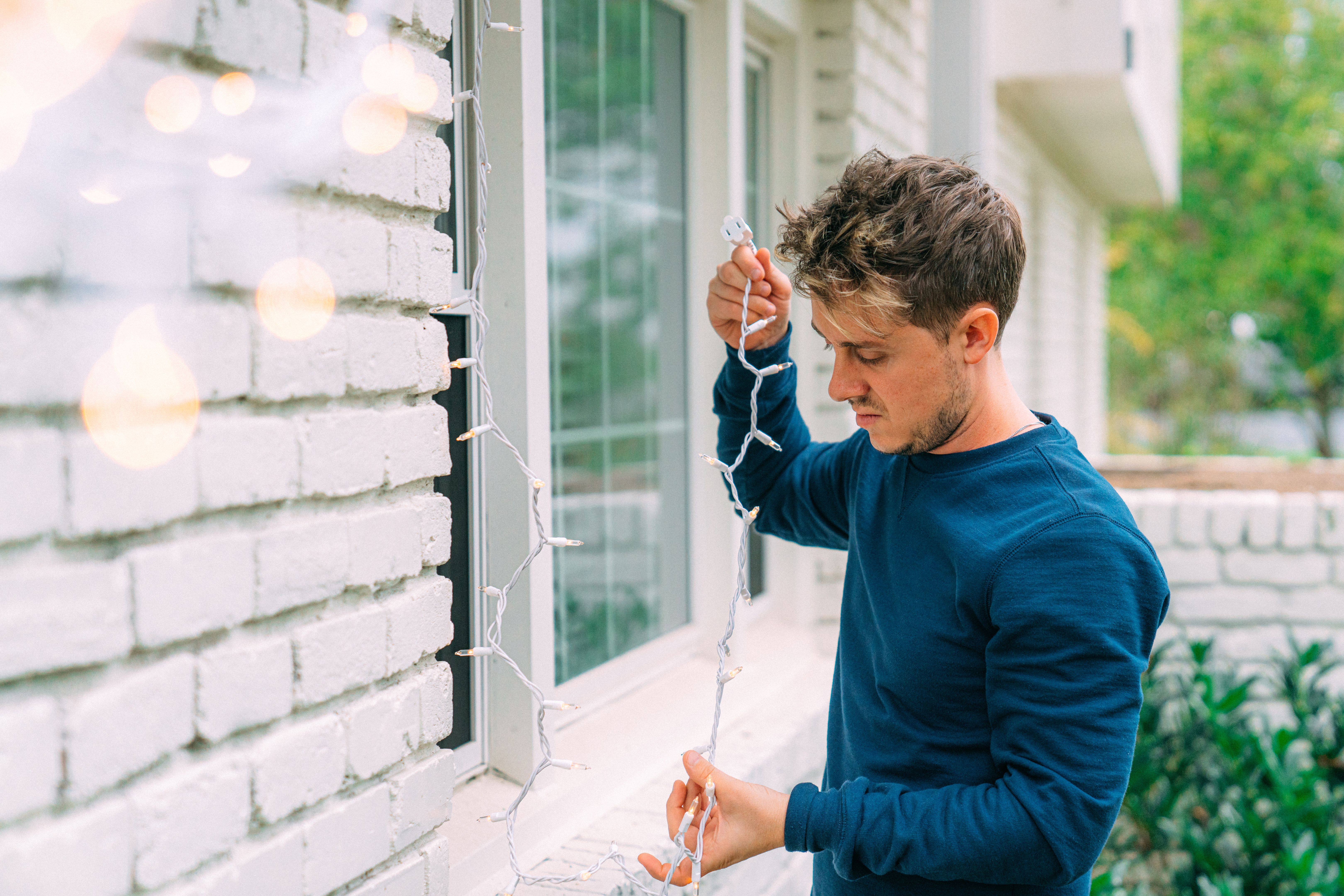 Young Man Untangling Christmas Lights, Decorating for Christmas Holiday