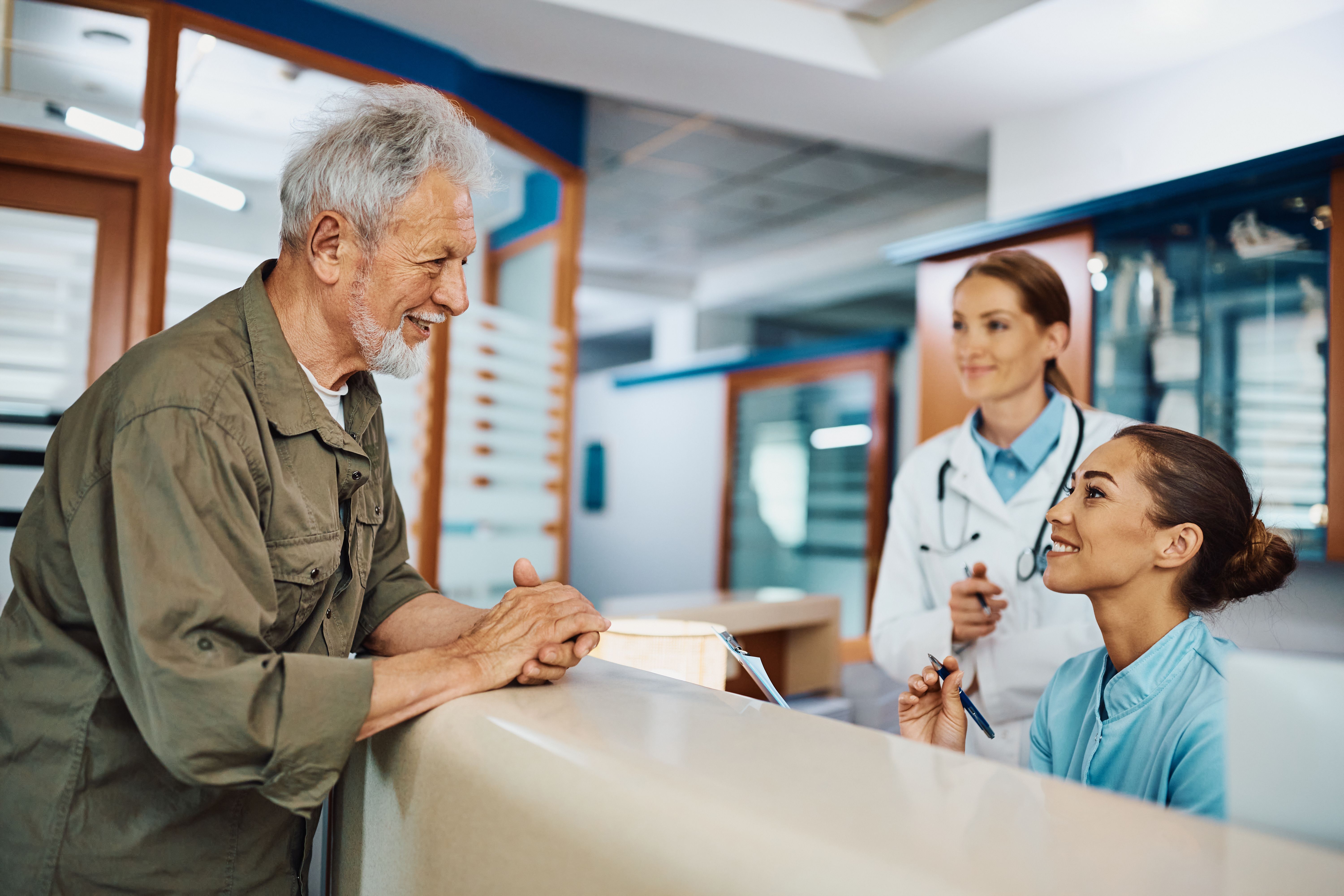 Happy senior man talking to nurse while checking in at doctor's office.