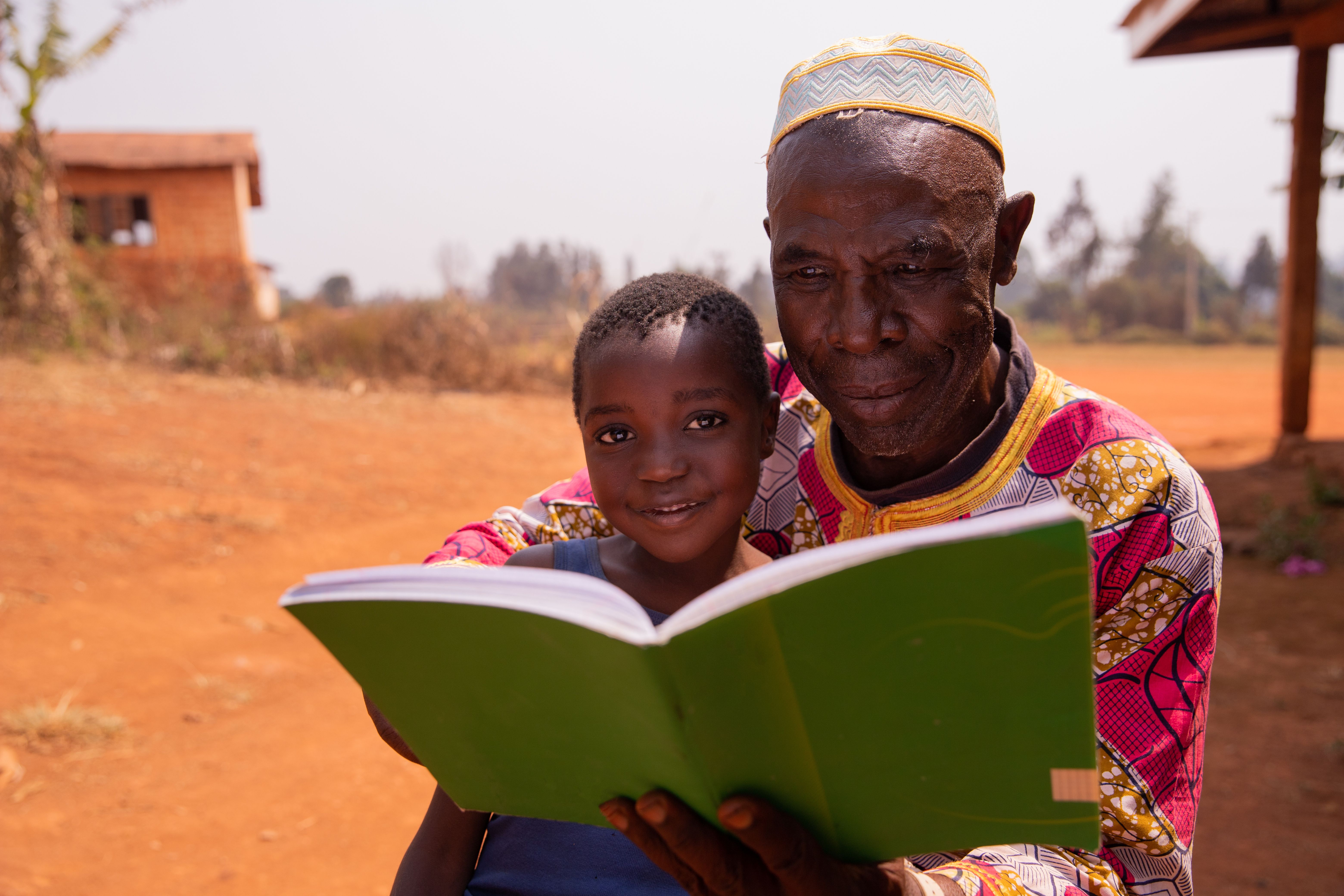 African grand father educating his grandson outdoor under the sun. Education concept