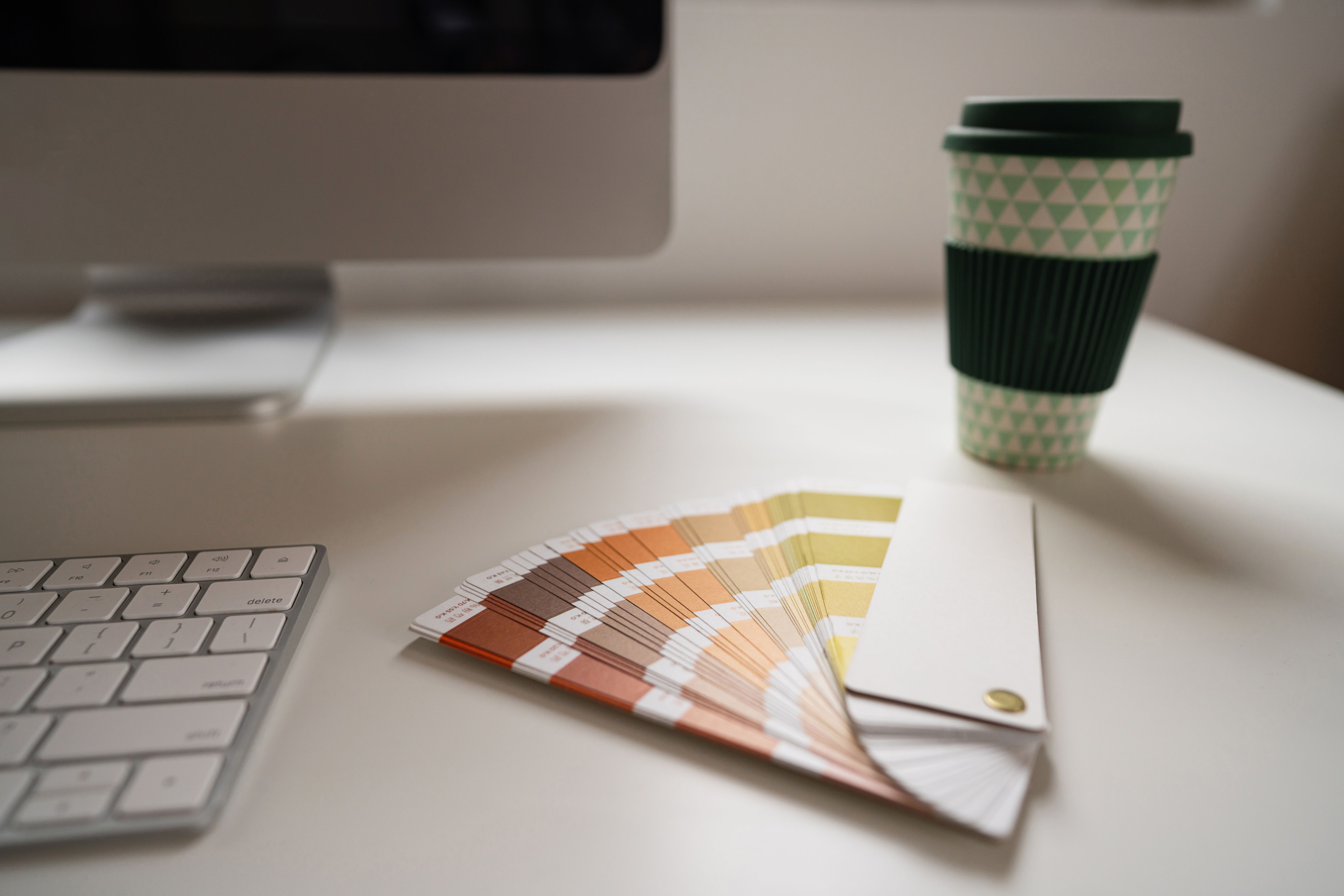 Close up of the computer, color swatch and coffee cup on the desk in the office Close up of the computer, color swatch and coffee cup on the desk in the office