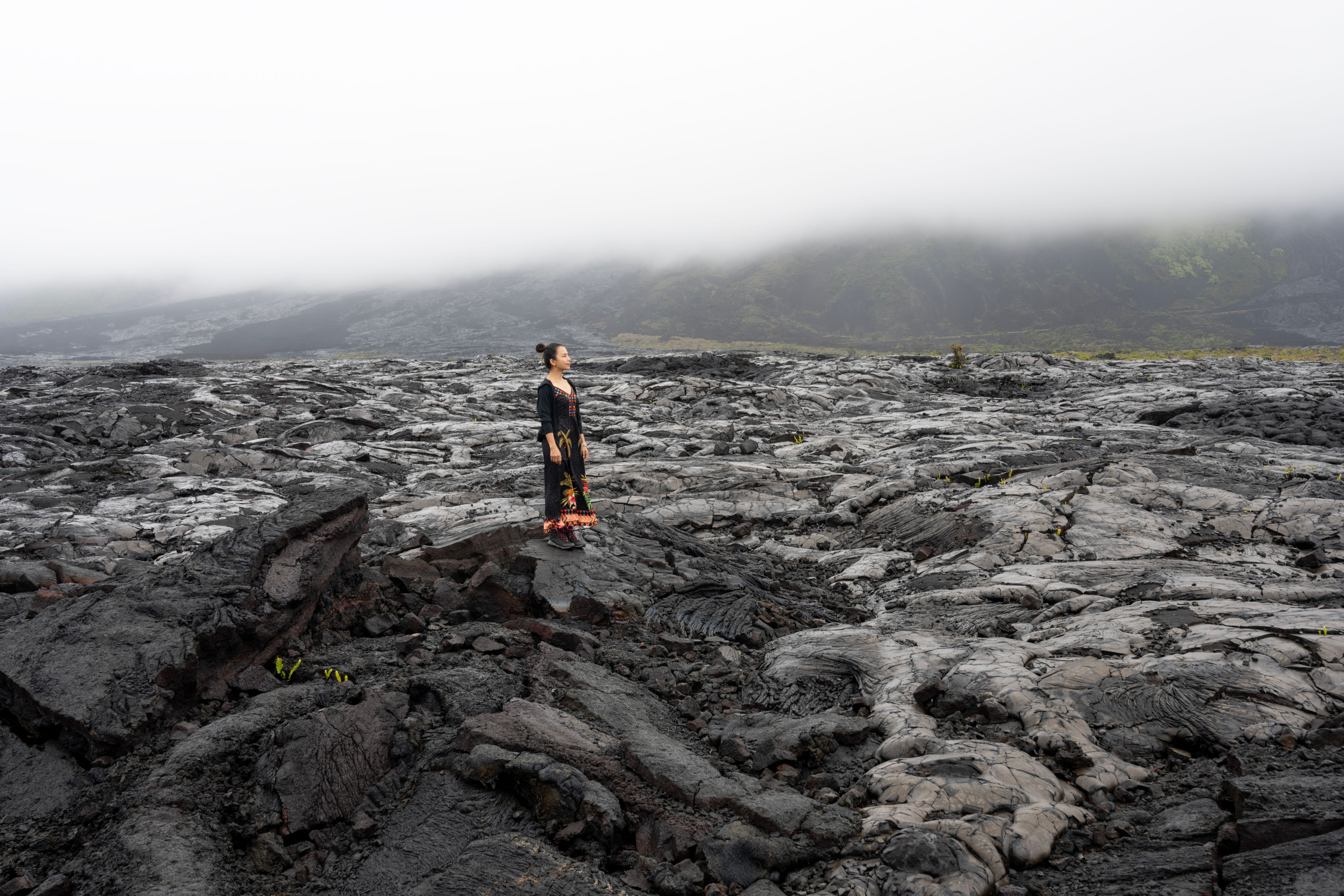 Woman standing on lava volcano rocks