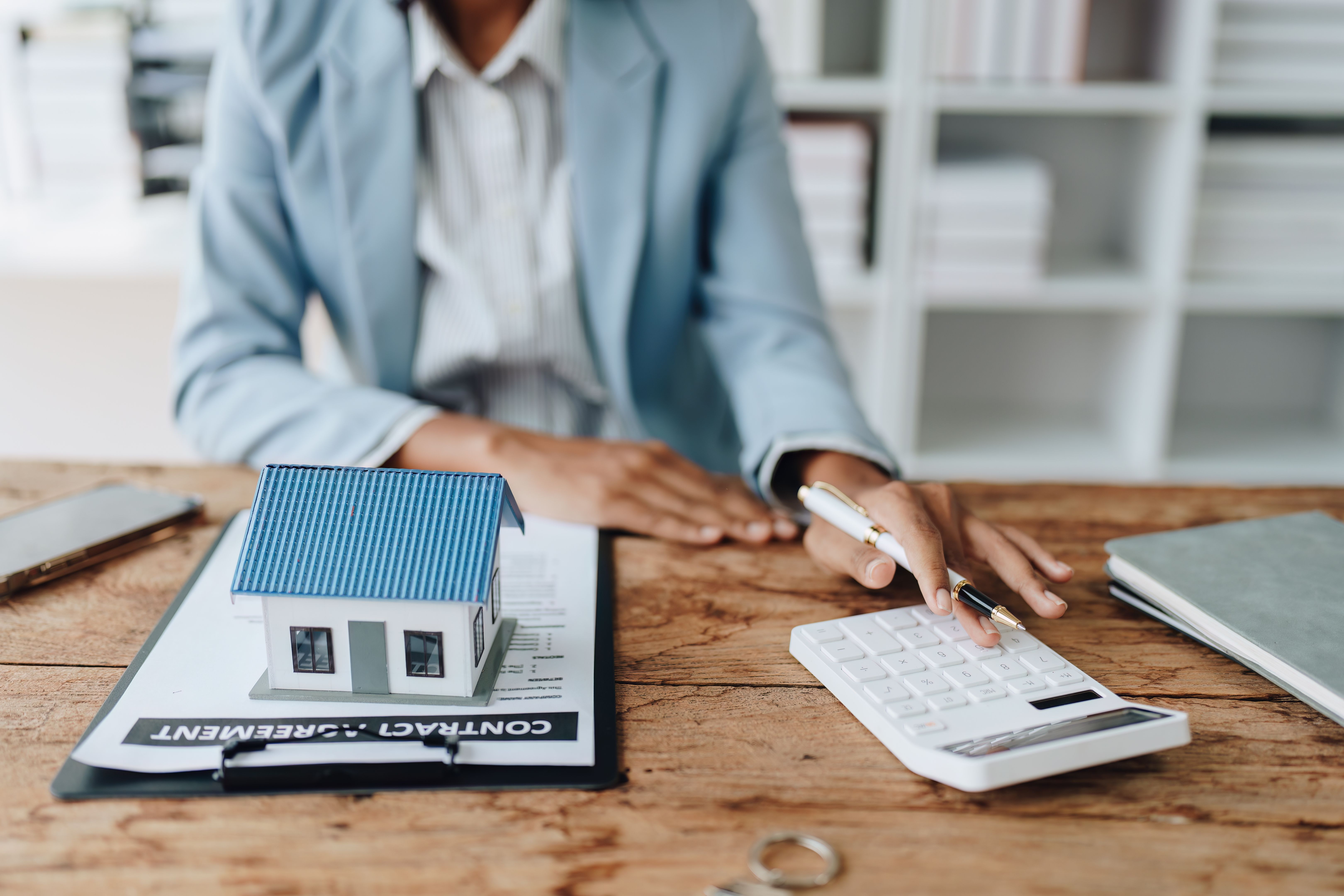 Real estate agent, African American businesswoman Africans use smartphone and calculators to offer mortgages to their clients. Home mortgage and insurance finance concepts.