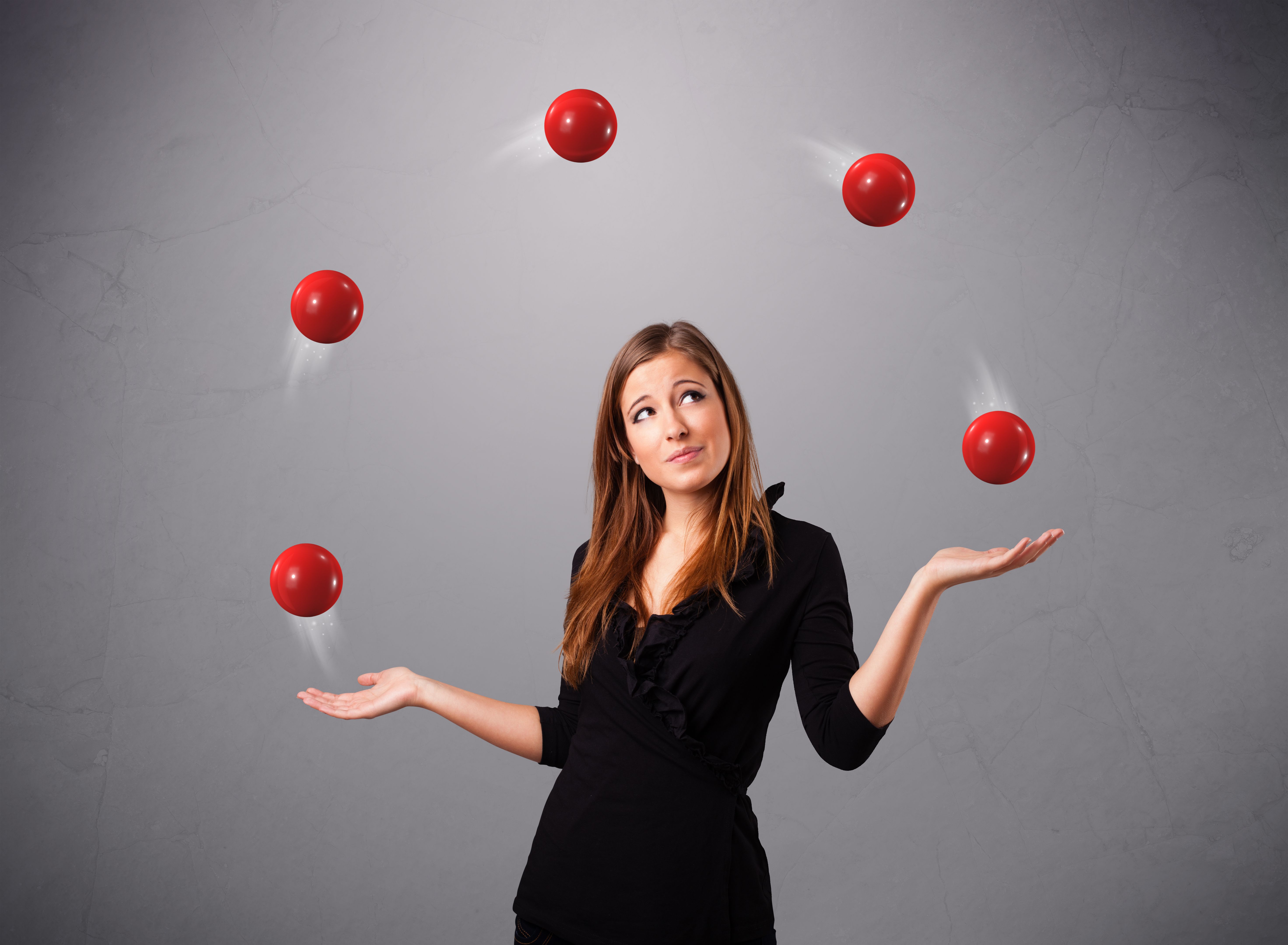 young girl standing and juggling with red balls