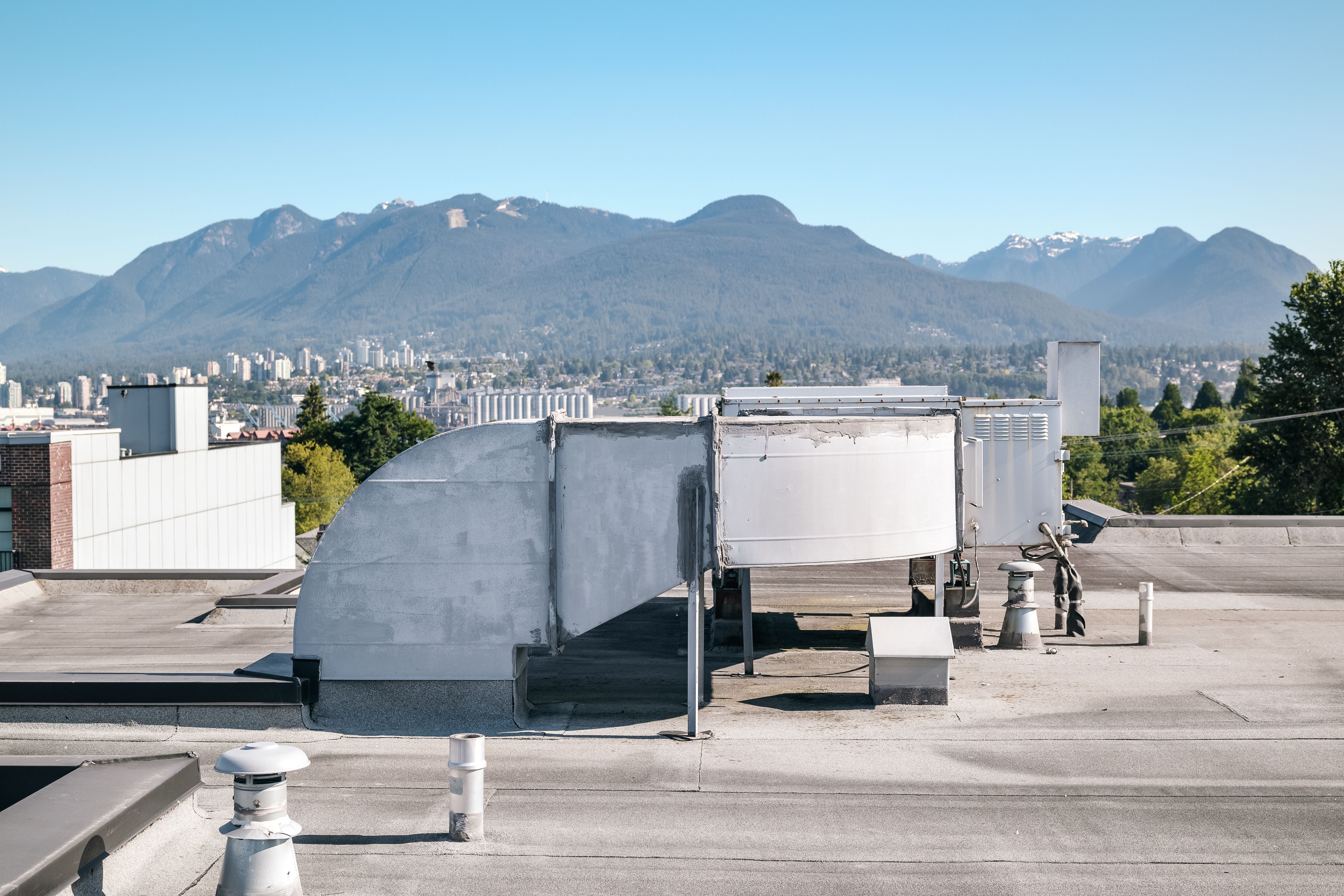 Hvac unit on flat roof with defocused city and mountains.