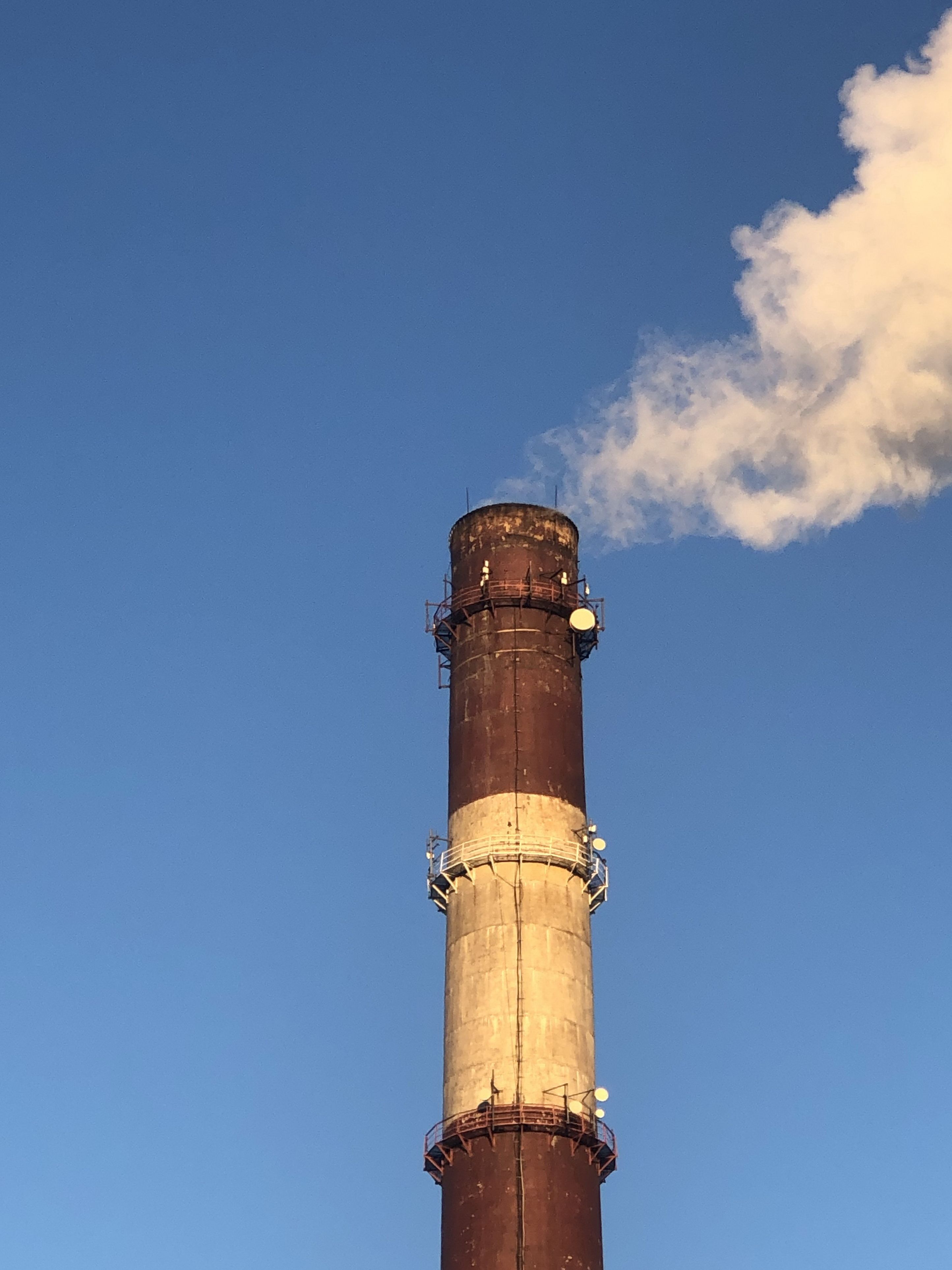tall striped power plant chimney smokes