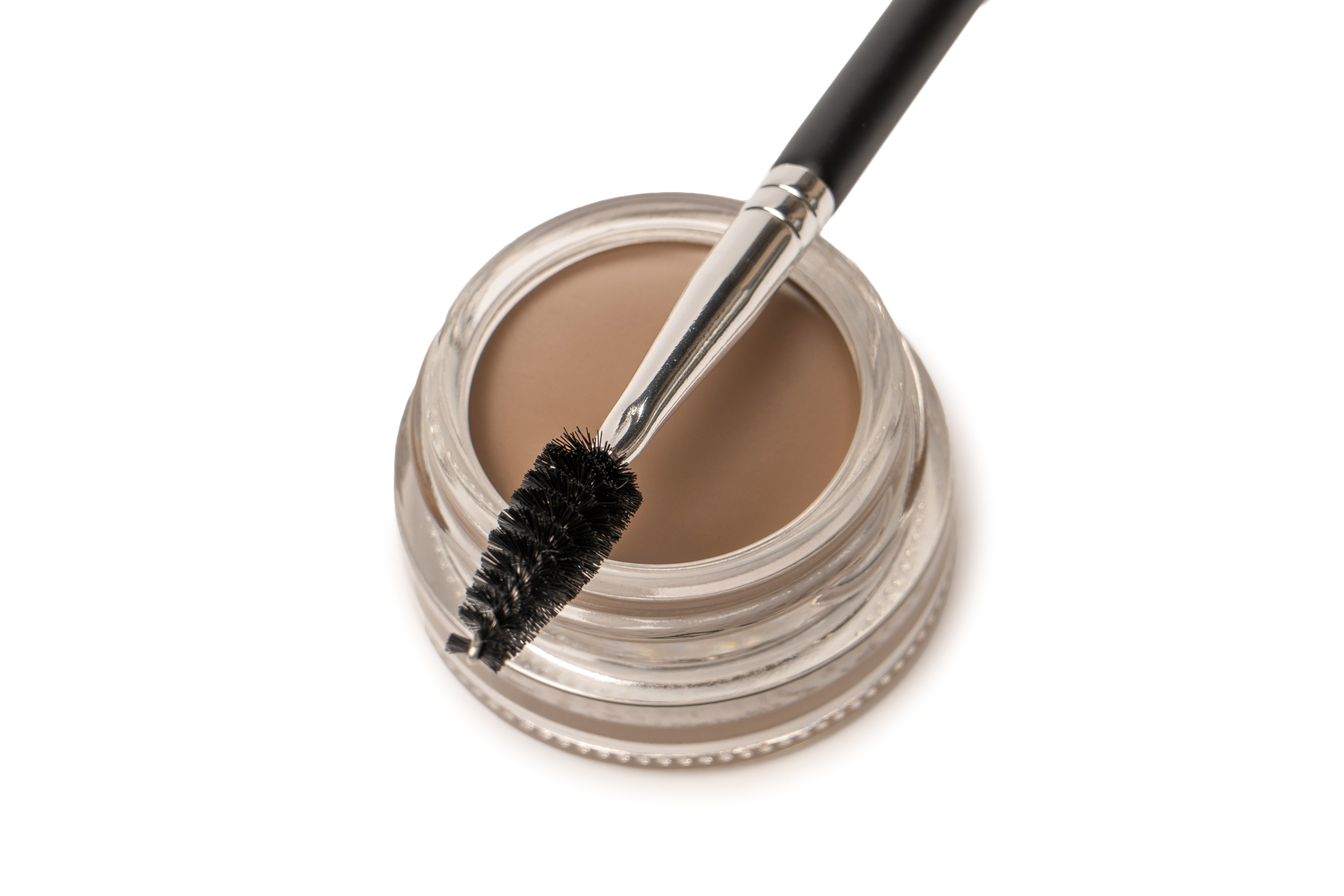 A brow pomade in blonde shade with brush isolated on a white background.