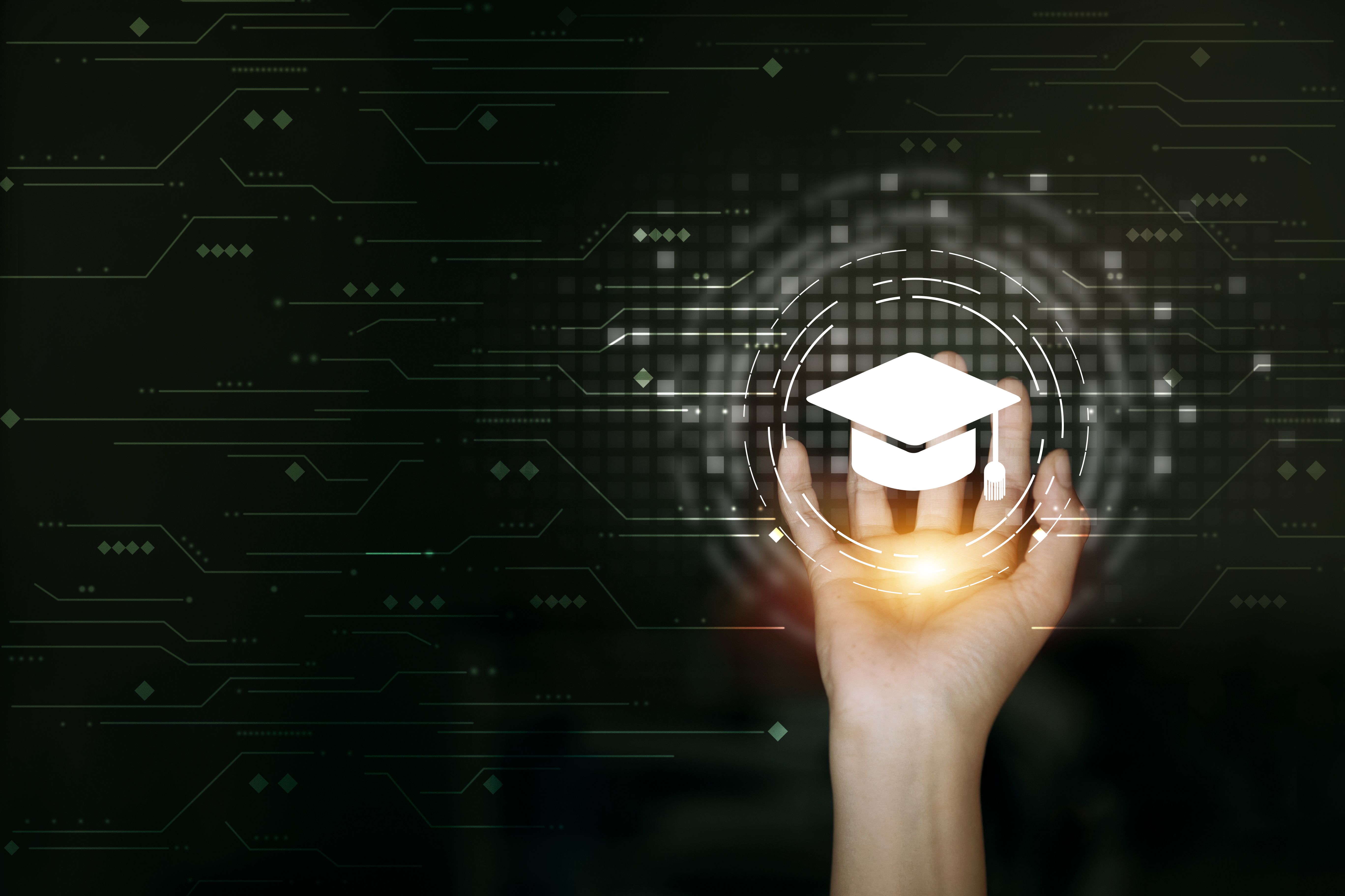 A hand holds a holographic graduation cap, symbolizing digital learning