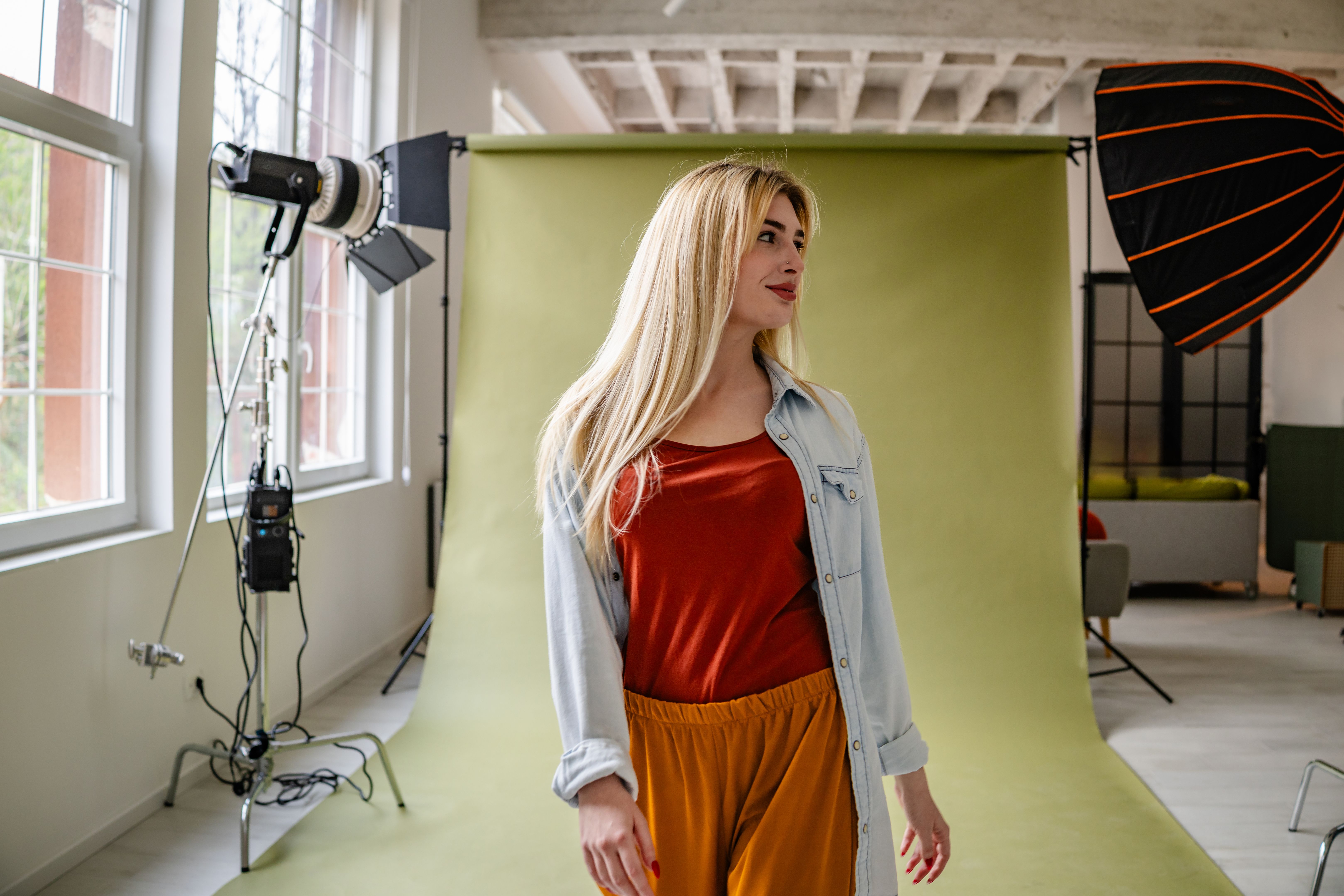 Young blonde woman showcases modern fashion in a vibrant studio setting with professional lighting