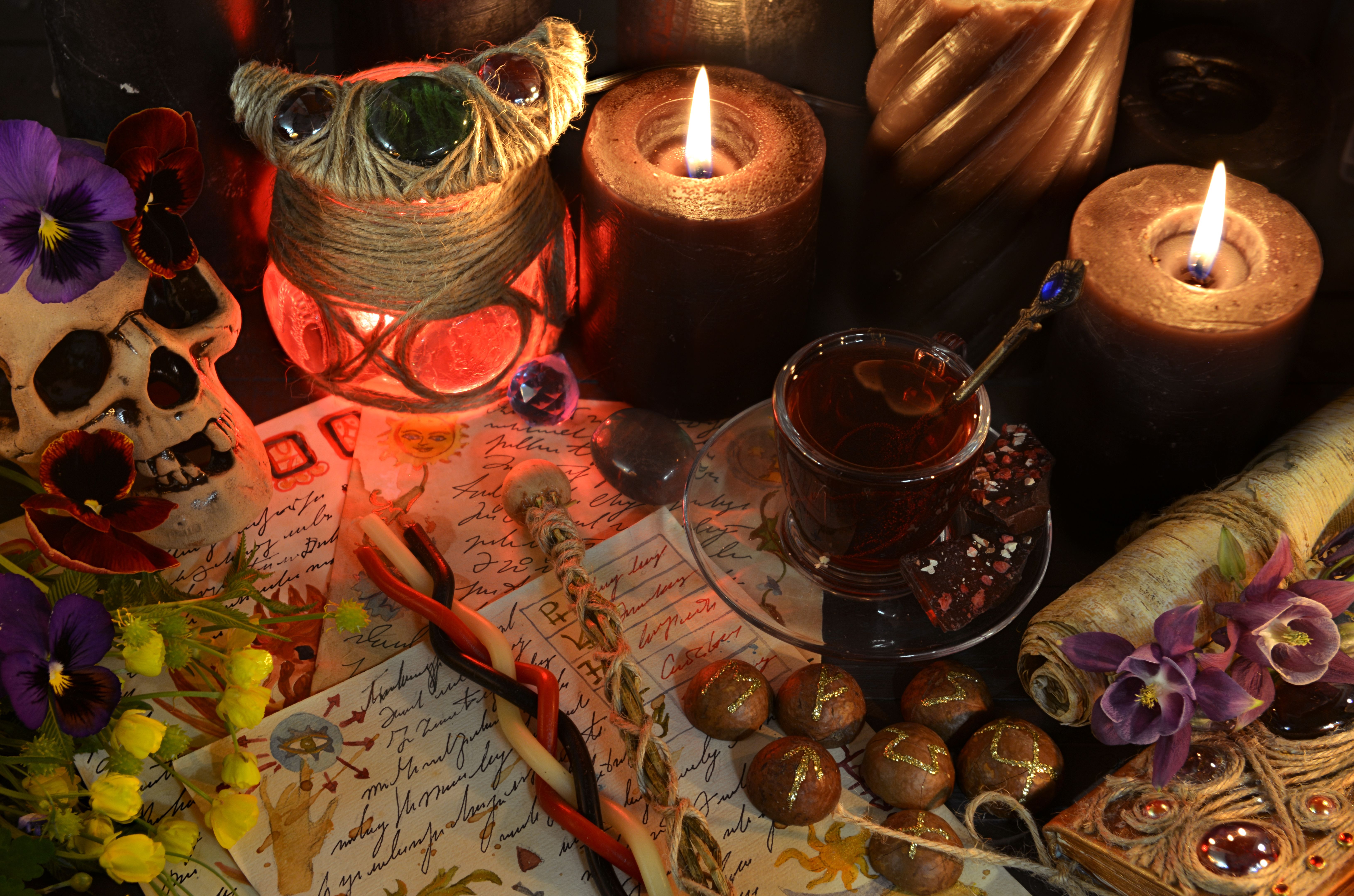 Still life with skull, magic wands, manuscript and candles on witch ritual table. Occult, esoteric and witchcraft concept. Mystic background with vintage objects