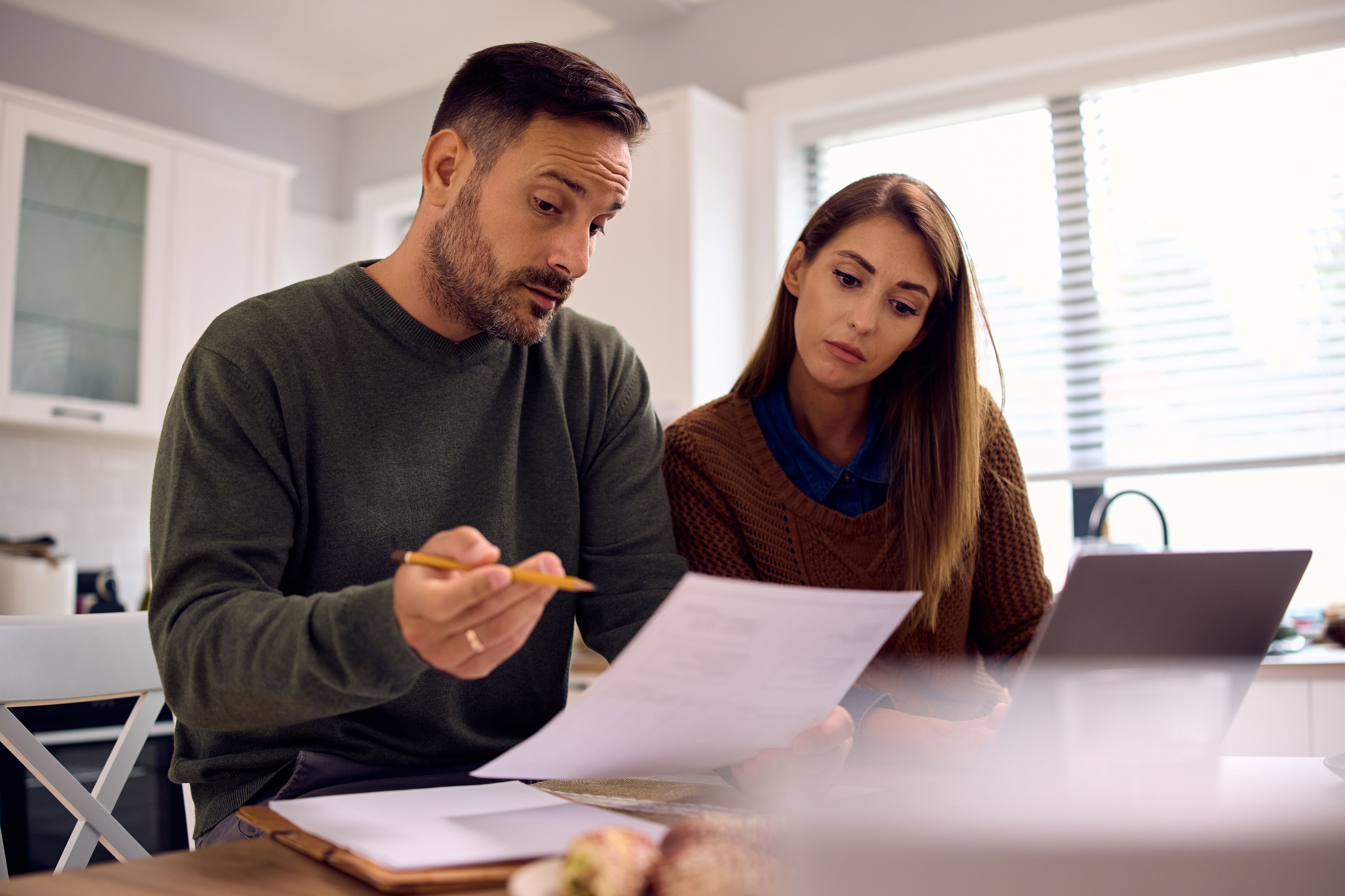 Mid adult couple going through their financial reports at home. Mid adult couple going through their financial reports at home.