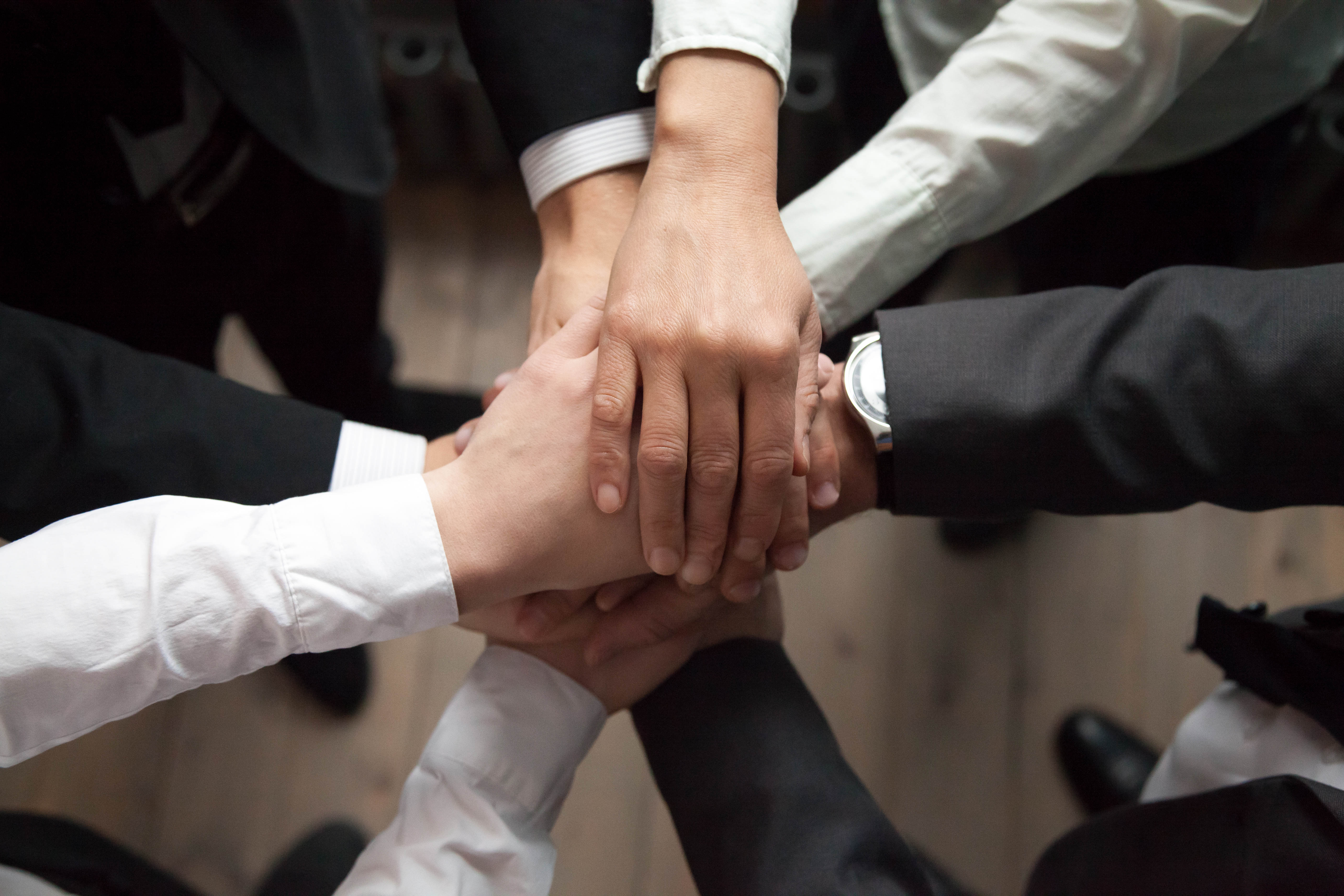 Motivated business people put hands together, trust and support concept