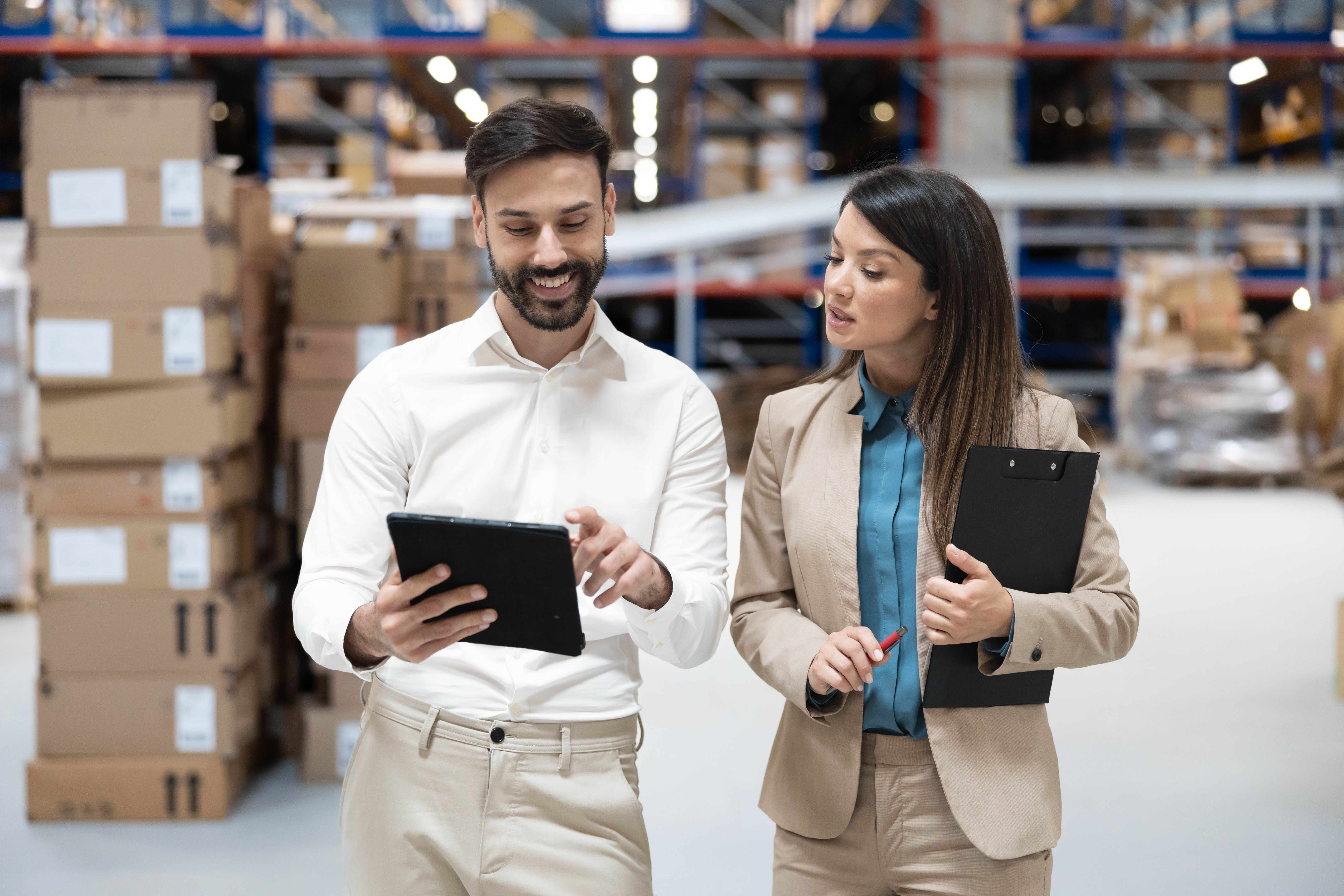 Warehouse supervisors reviewing inventory data on a digital tablet