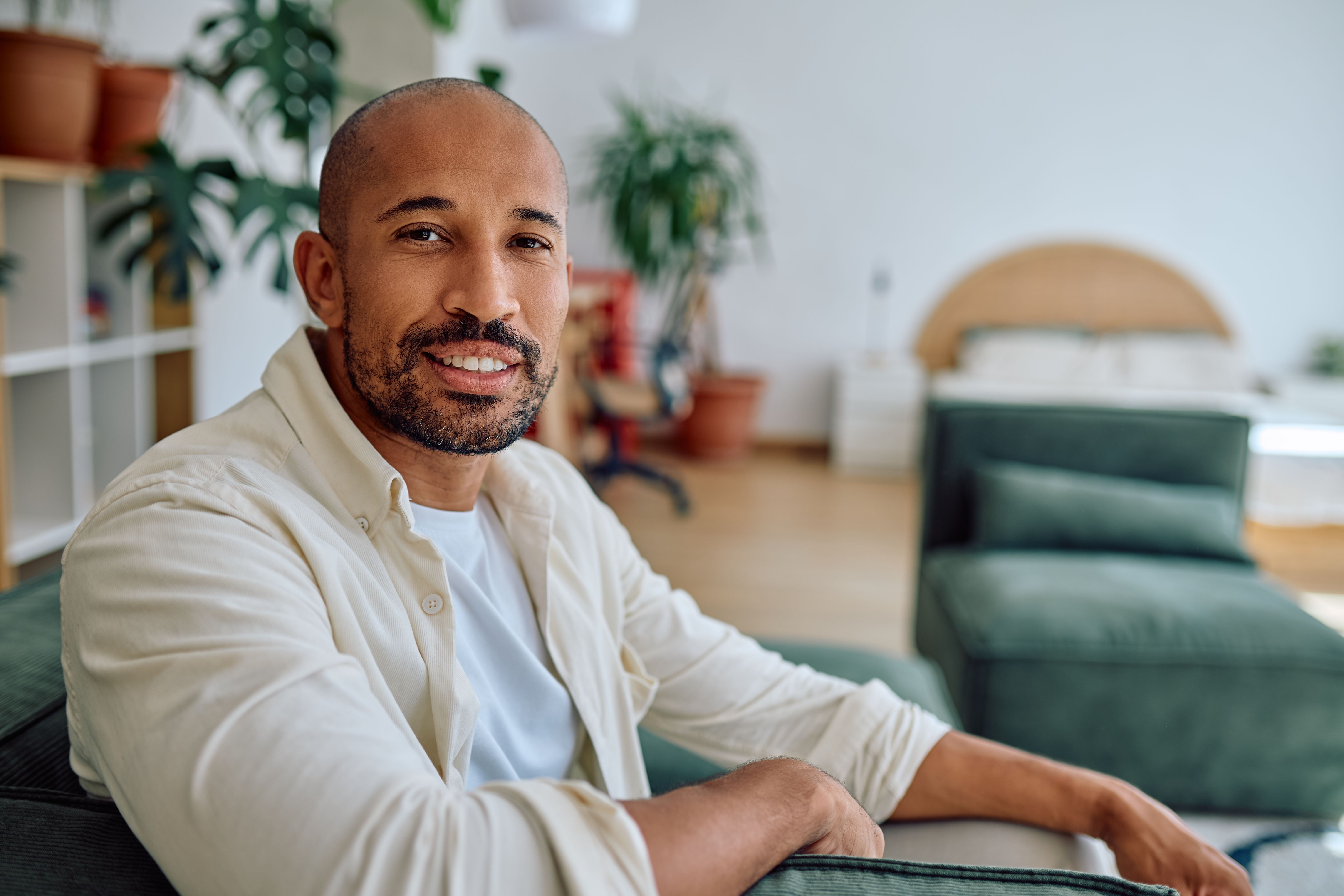 Happy african american man smiling while relaxing on sofa at home
