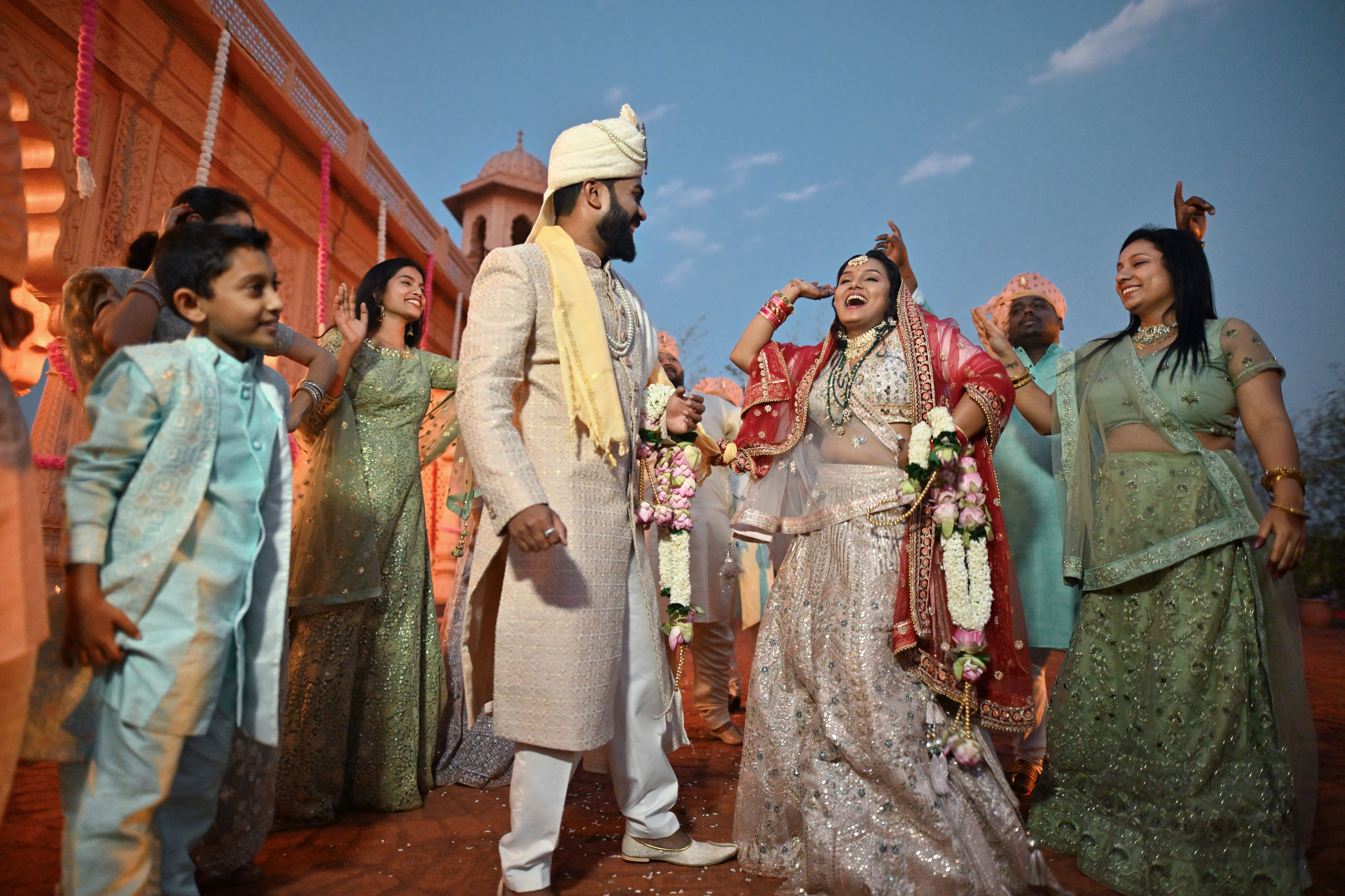 The radiant bride dances joyfully, while the groom and family happily admire her moment