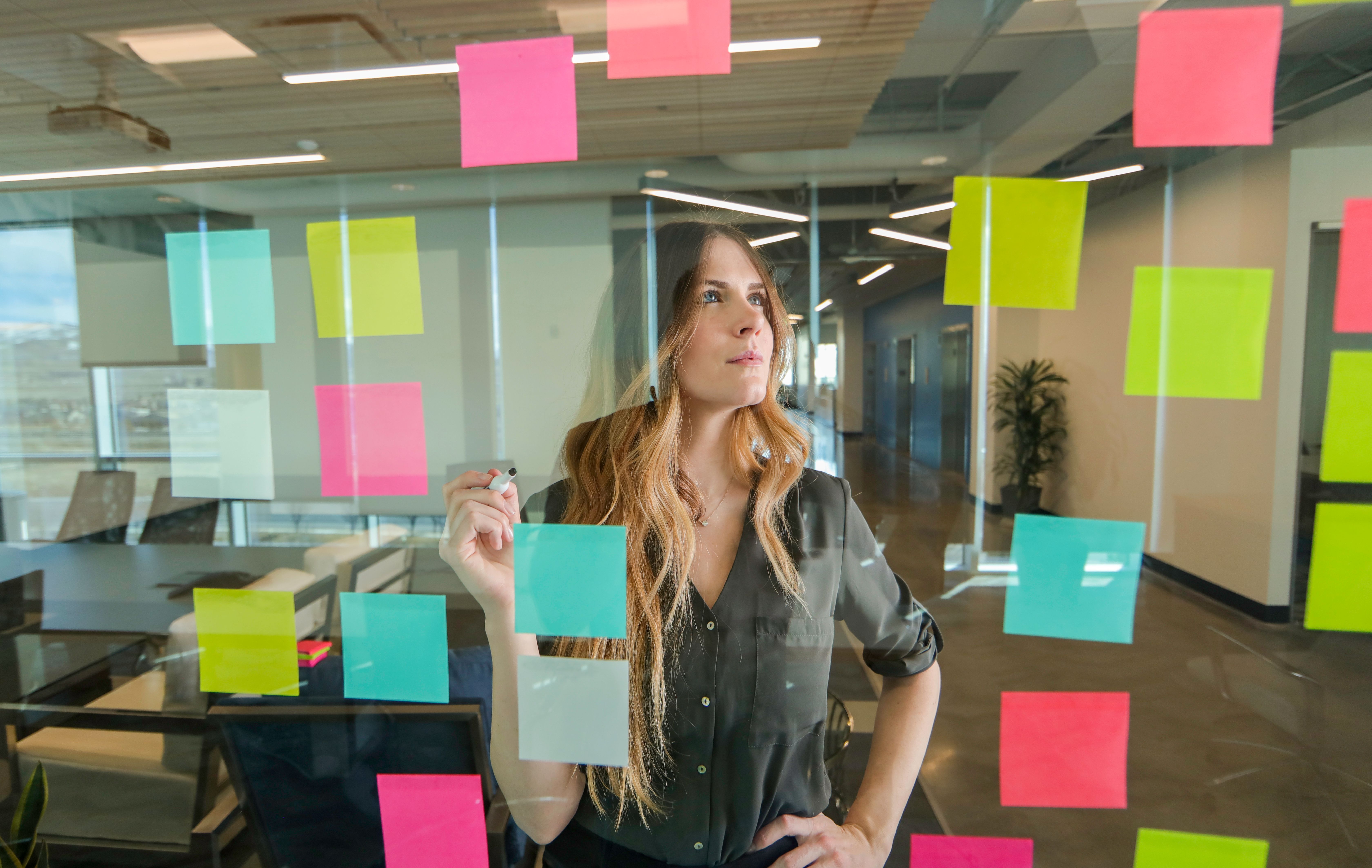 Woman using sticky notes on glass wall