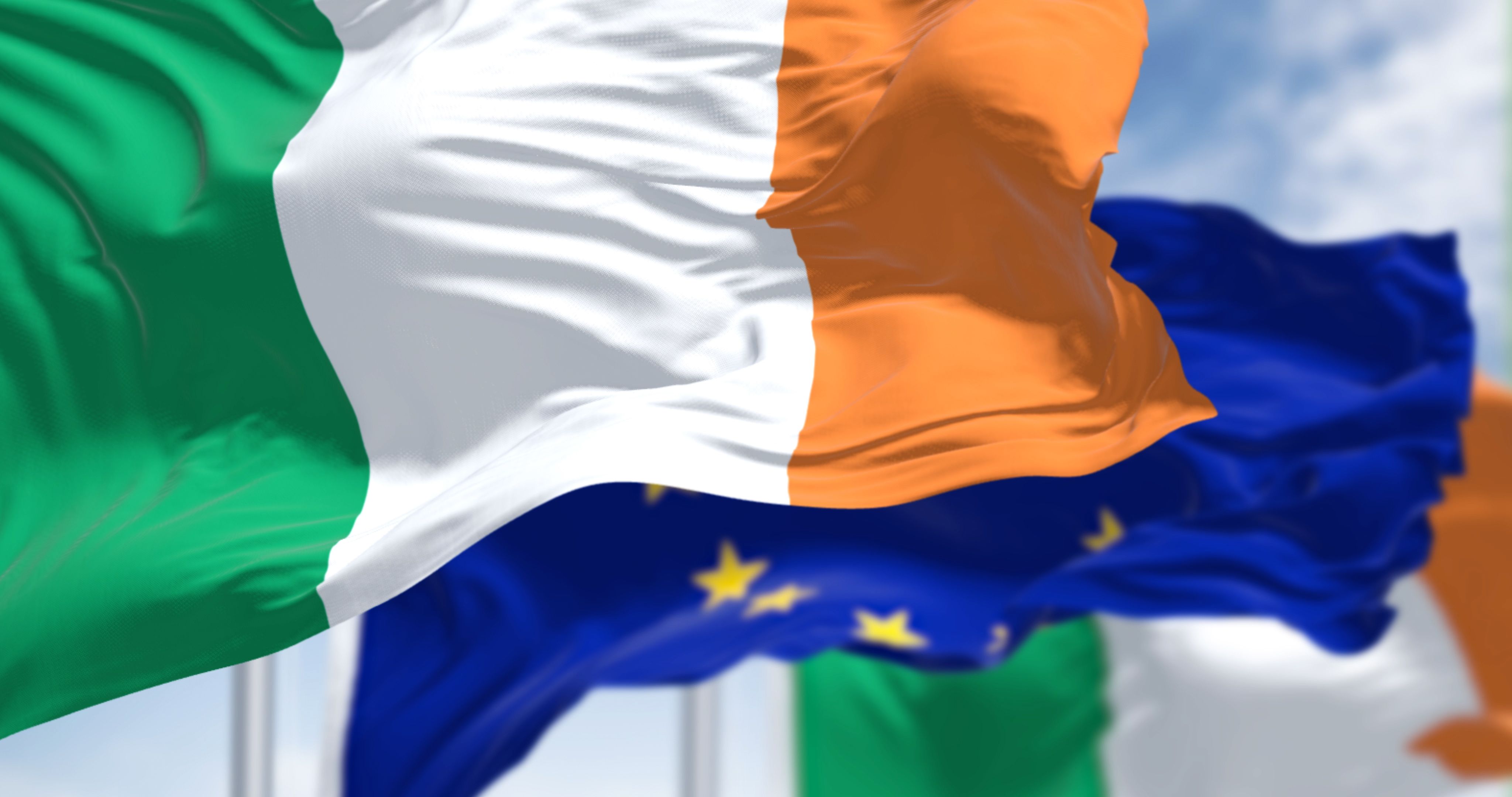 Detail of the national flag of Ireland waving in the wind with blurred european union flag
