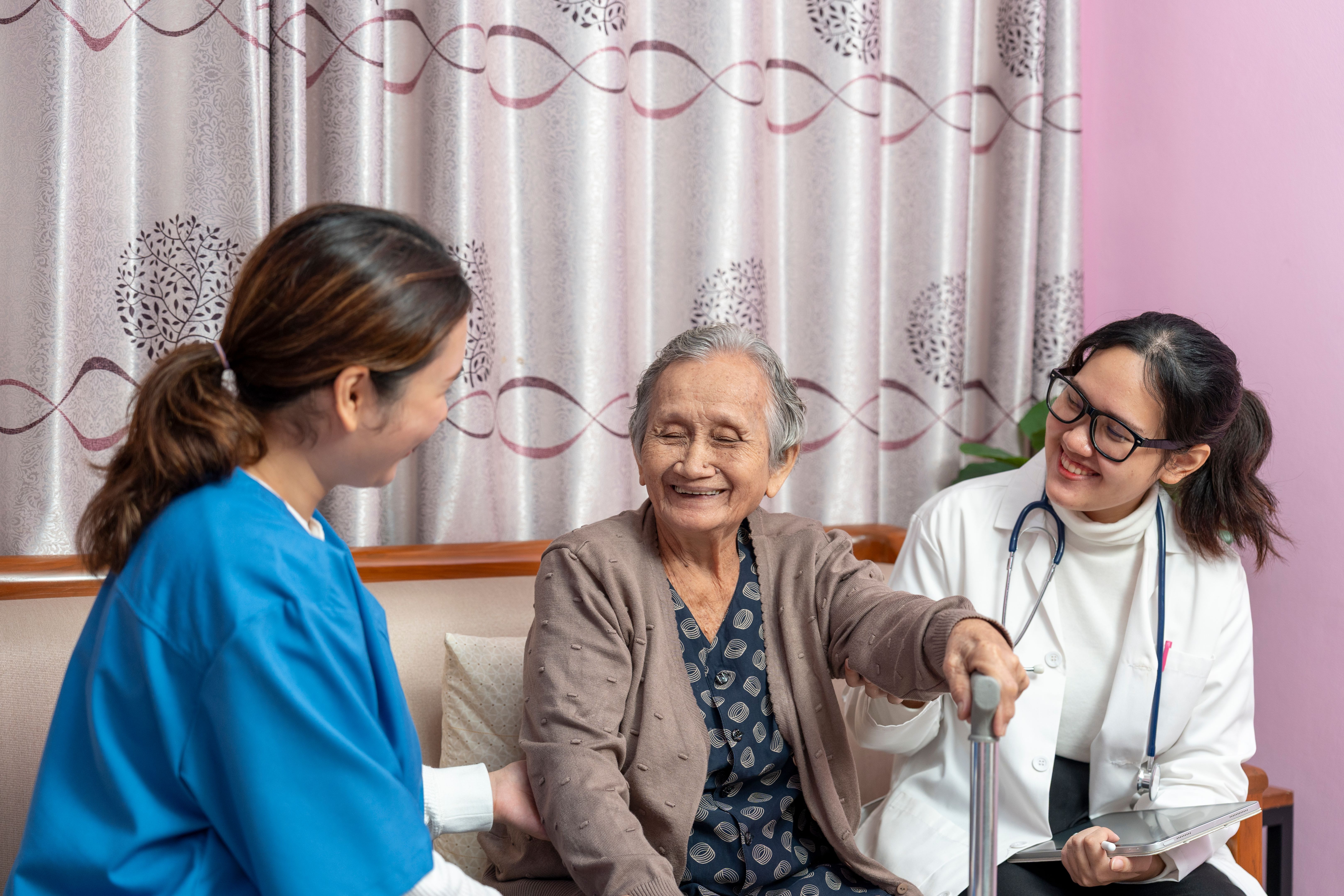 Young female doctor and nurse cares for an senior or elderly woman. Home caregiver.