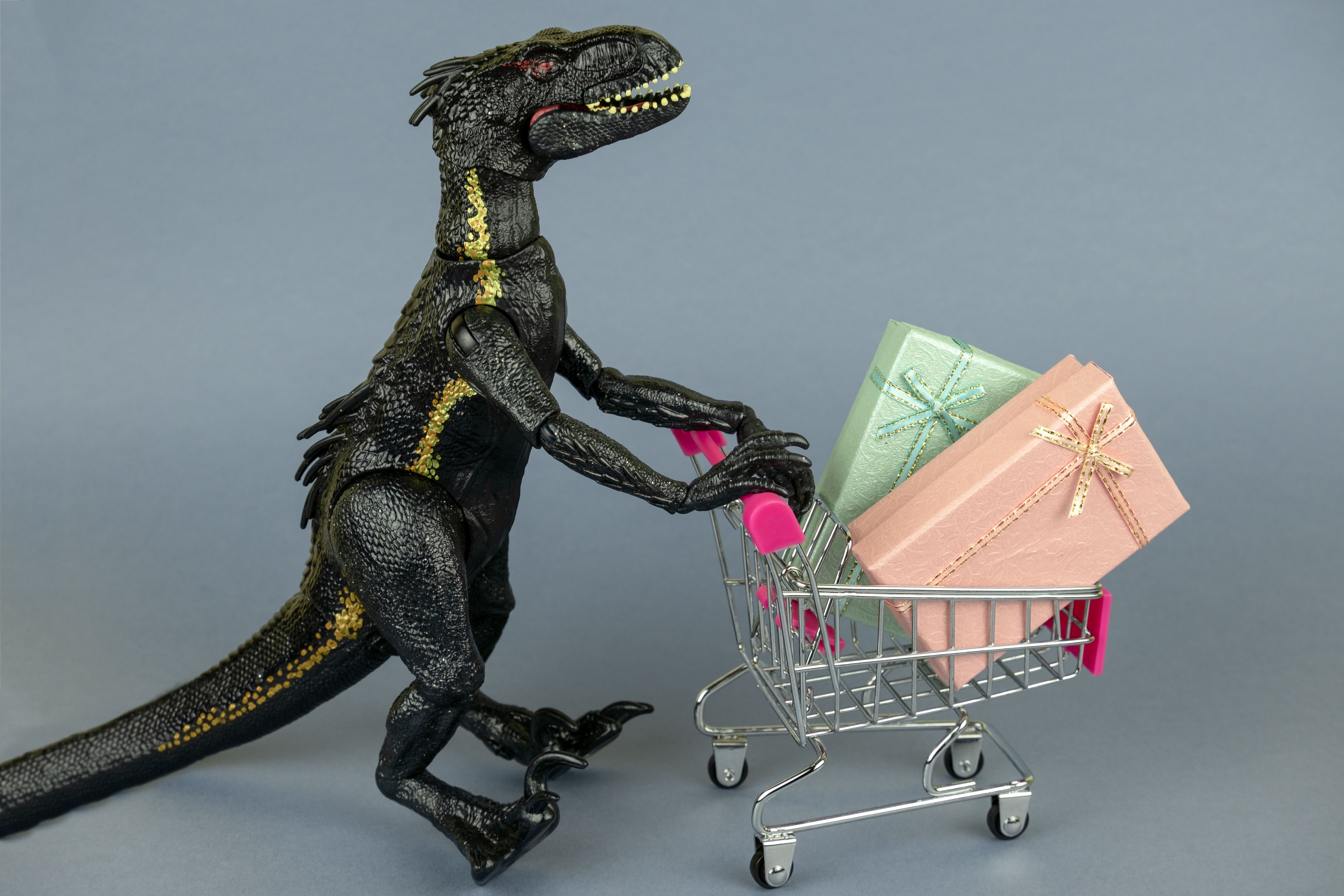 dinosaur toy with shopping cart full of present boxes