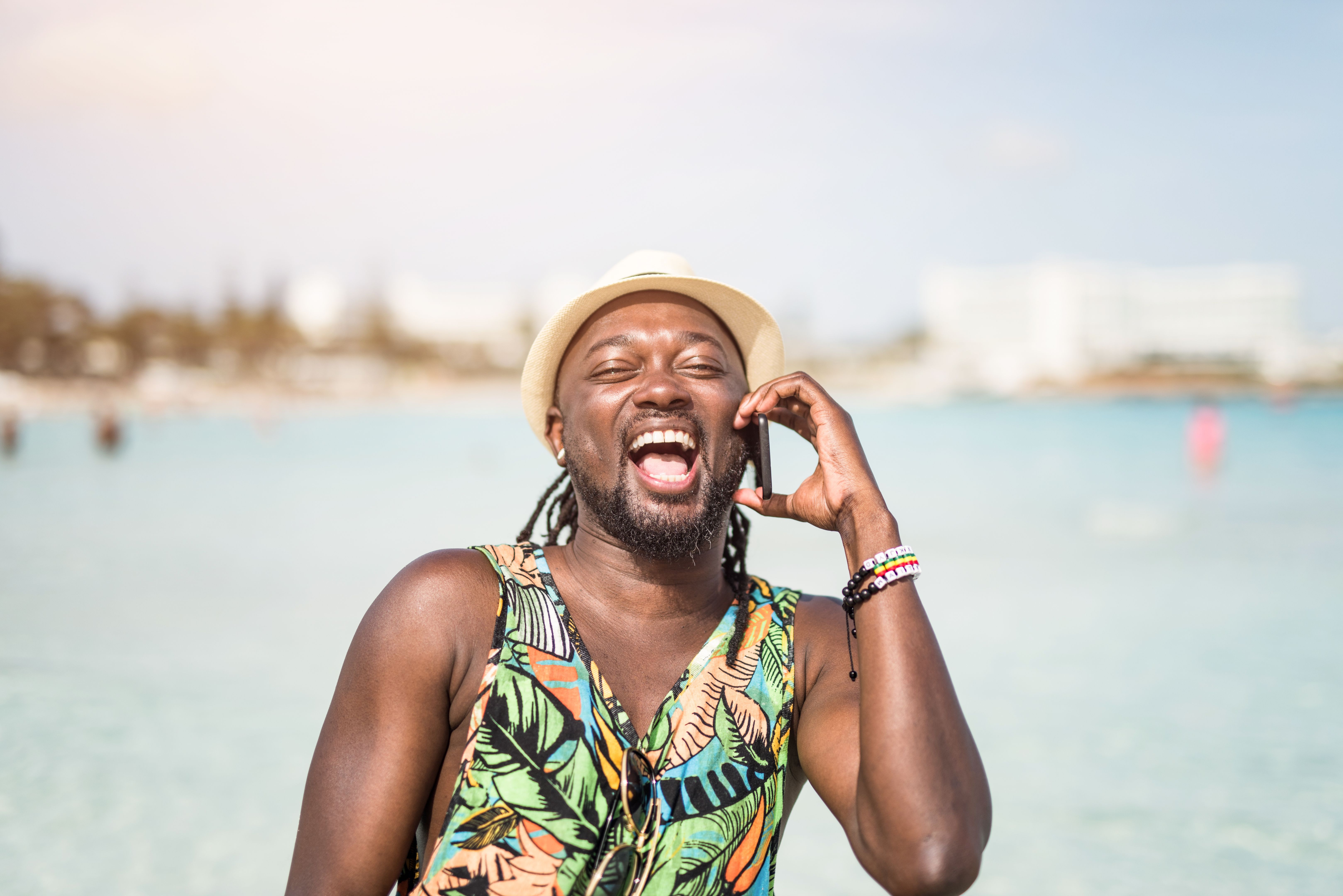 Happy African man using phone while on a beautiful beach on Cyprus island.