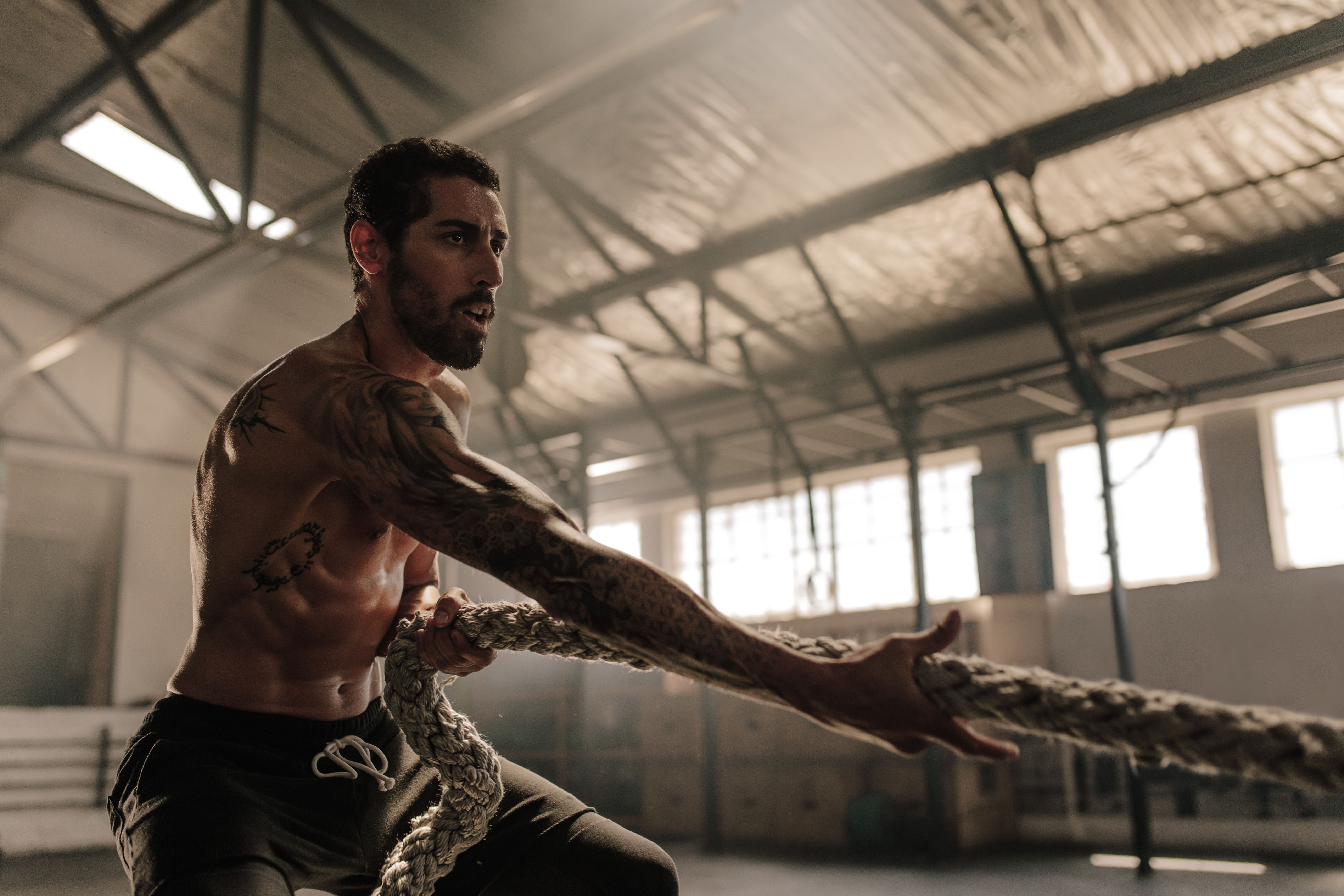 Strong man pulling heavy rope at gym