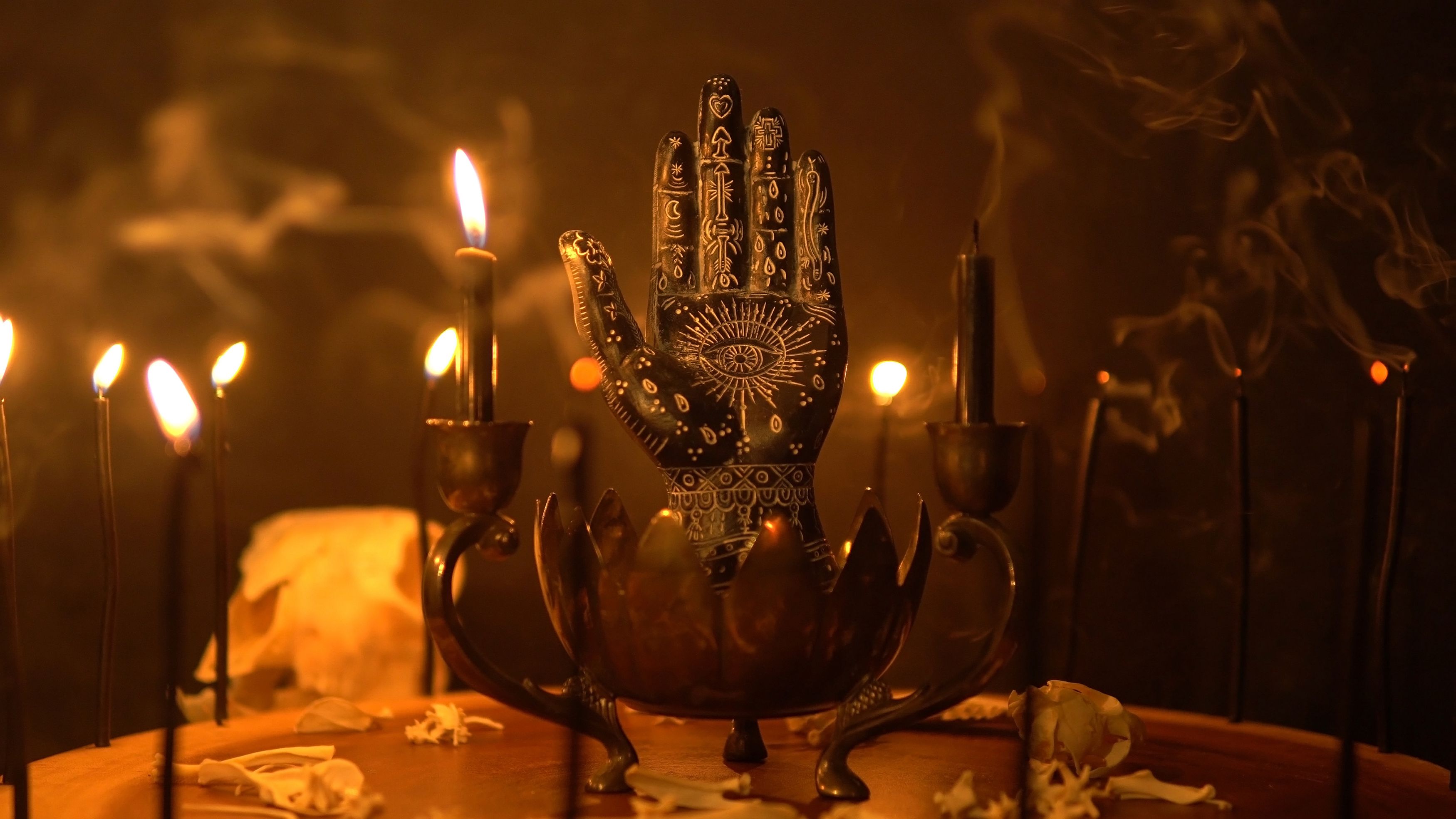 Palmistry and table statue of the black hand at fortune teller table. Mystic palm reading and magical black candles on candle holder. Occult knowledge and occultism. Spiritual mood. Palmistry and table statue of the black hand at fortune teller table. Mystic palm reading and magical black candles on candle holder. Occult knowledge and occultism. Spiritual mood.