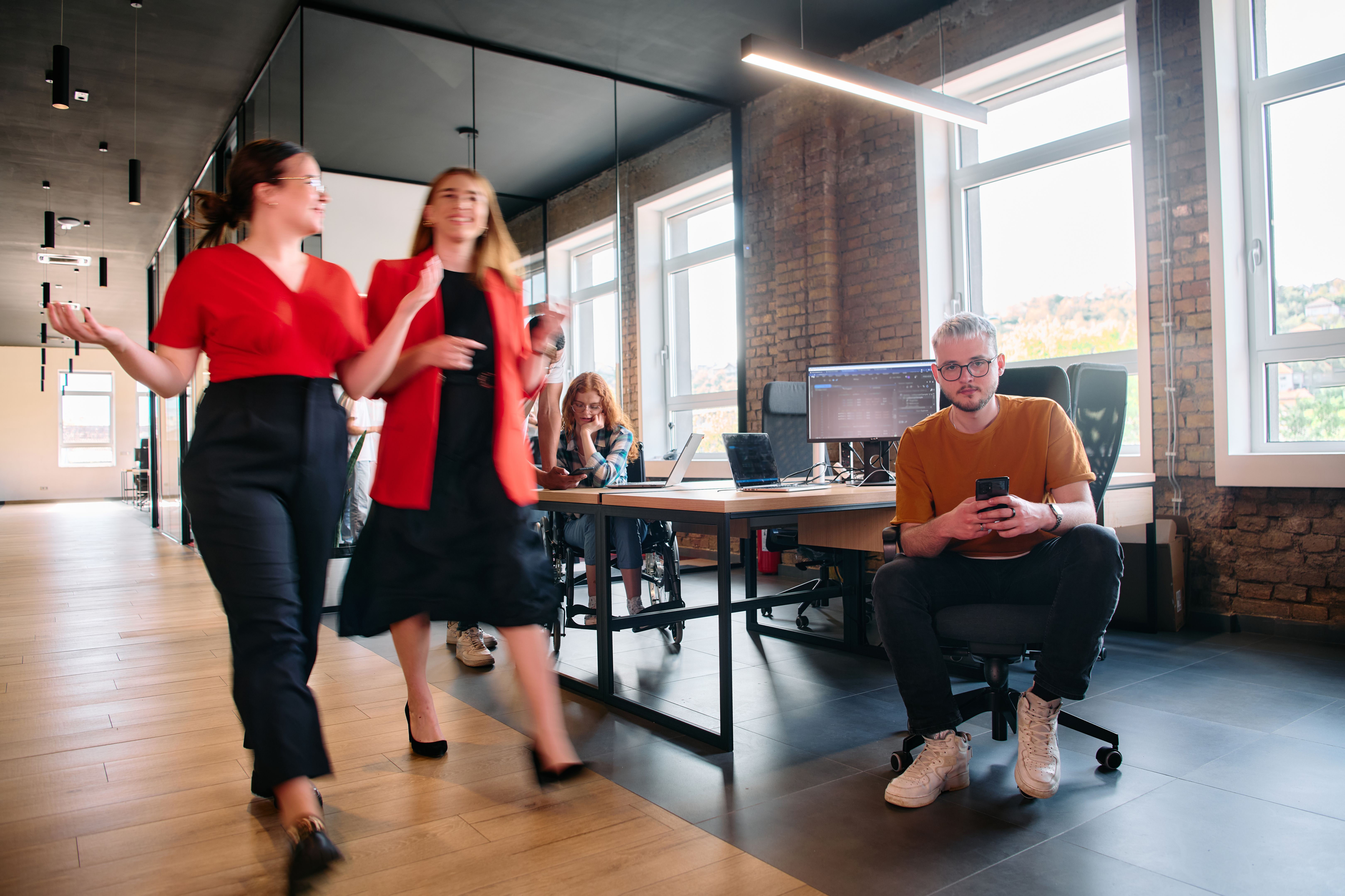 A diverse group of business professionals collaborates in a modern startup coworking center, utilizing a mix of paper-based and technological tools such as mobile phones and computers