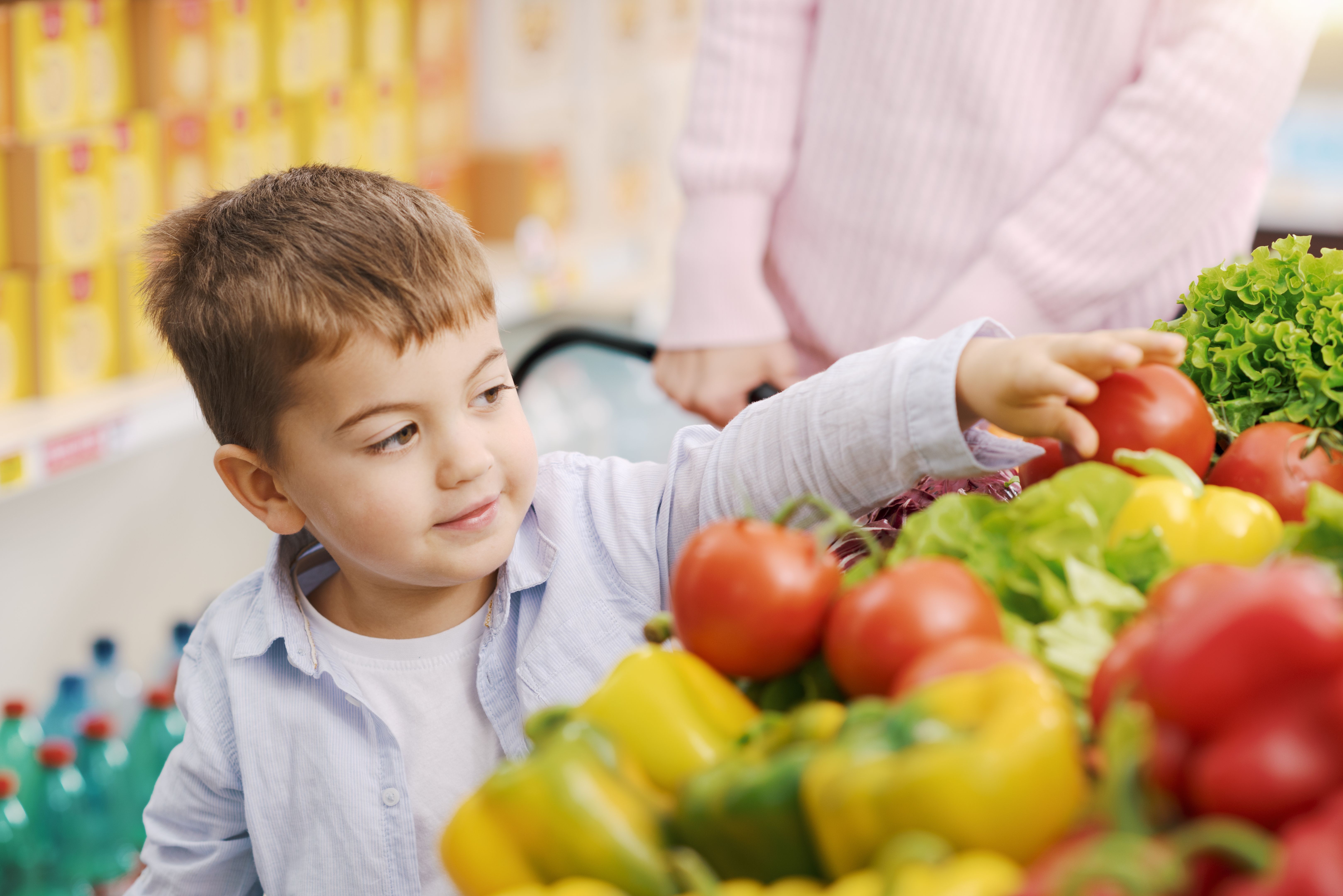Cute boy picking fresh vegetables at the supermarket