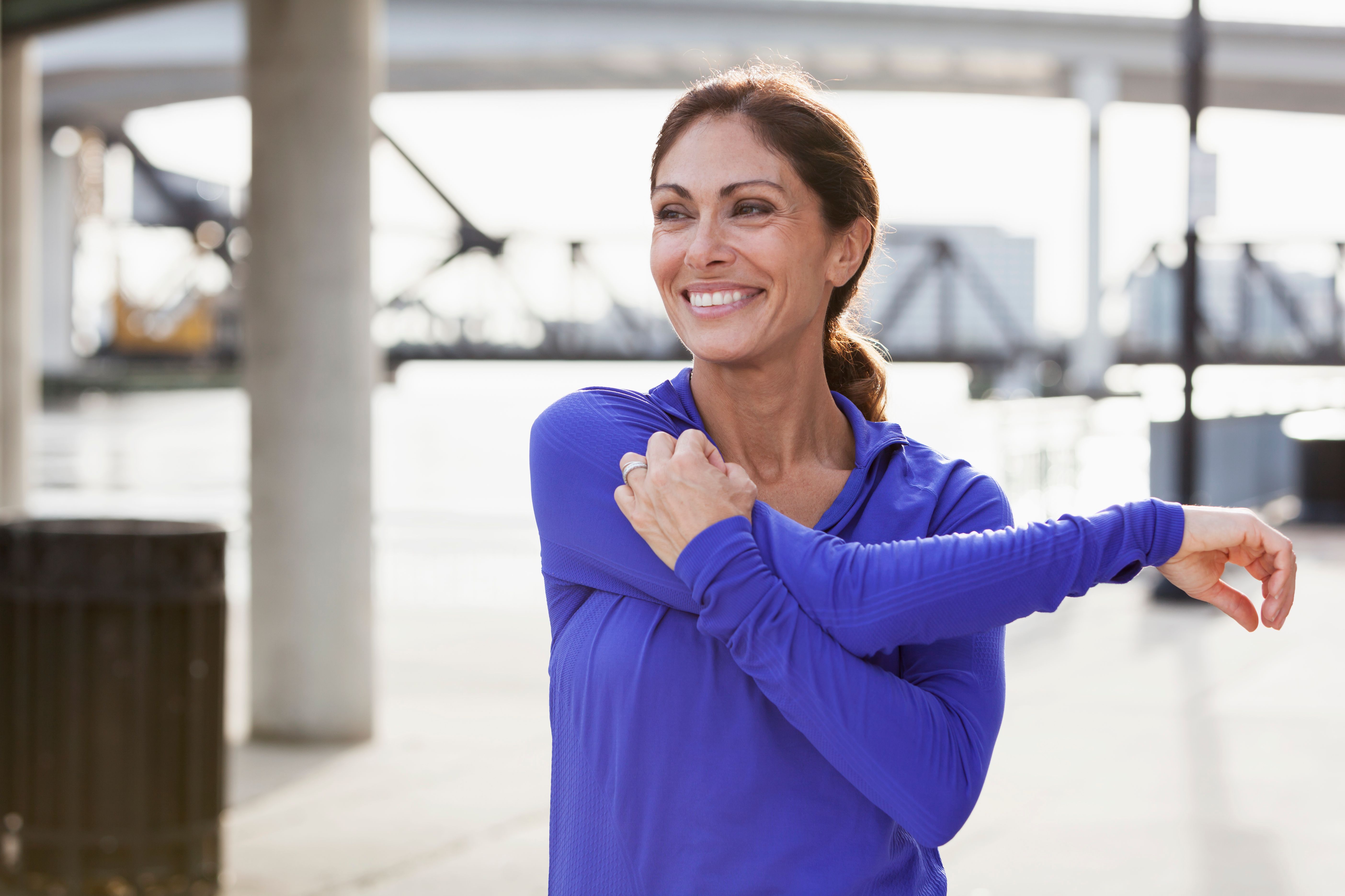 Mature woman stretching during a jog on waterfront