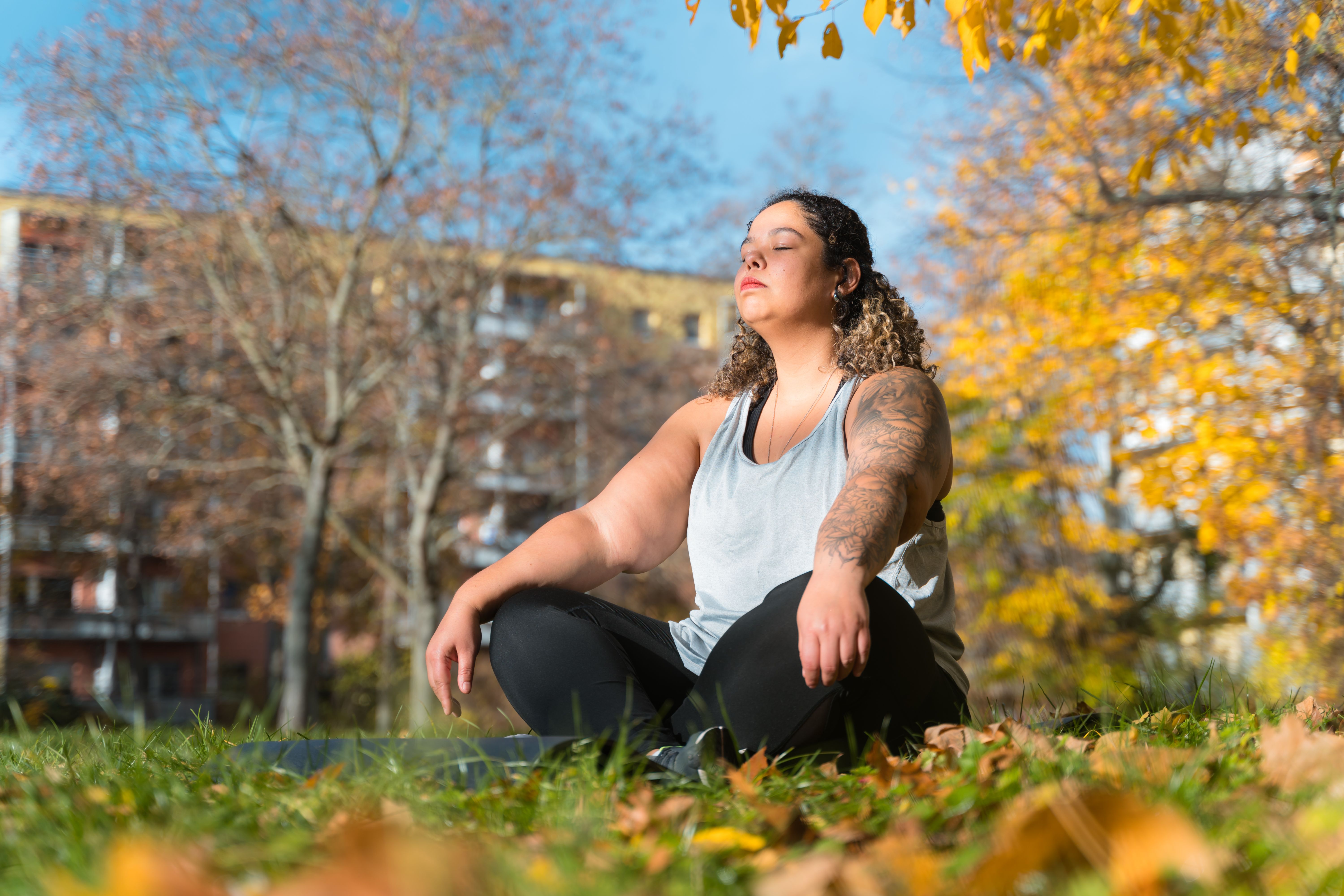 Brazilian woman meditating in park during autumn in dresden