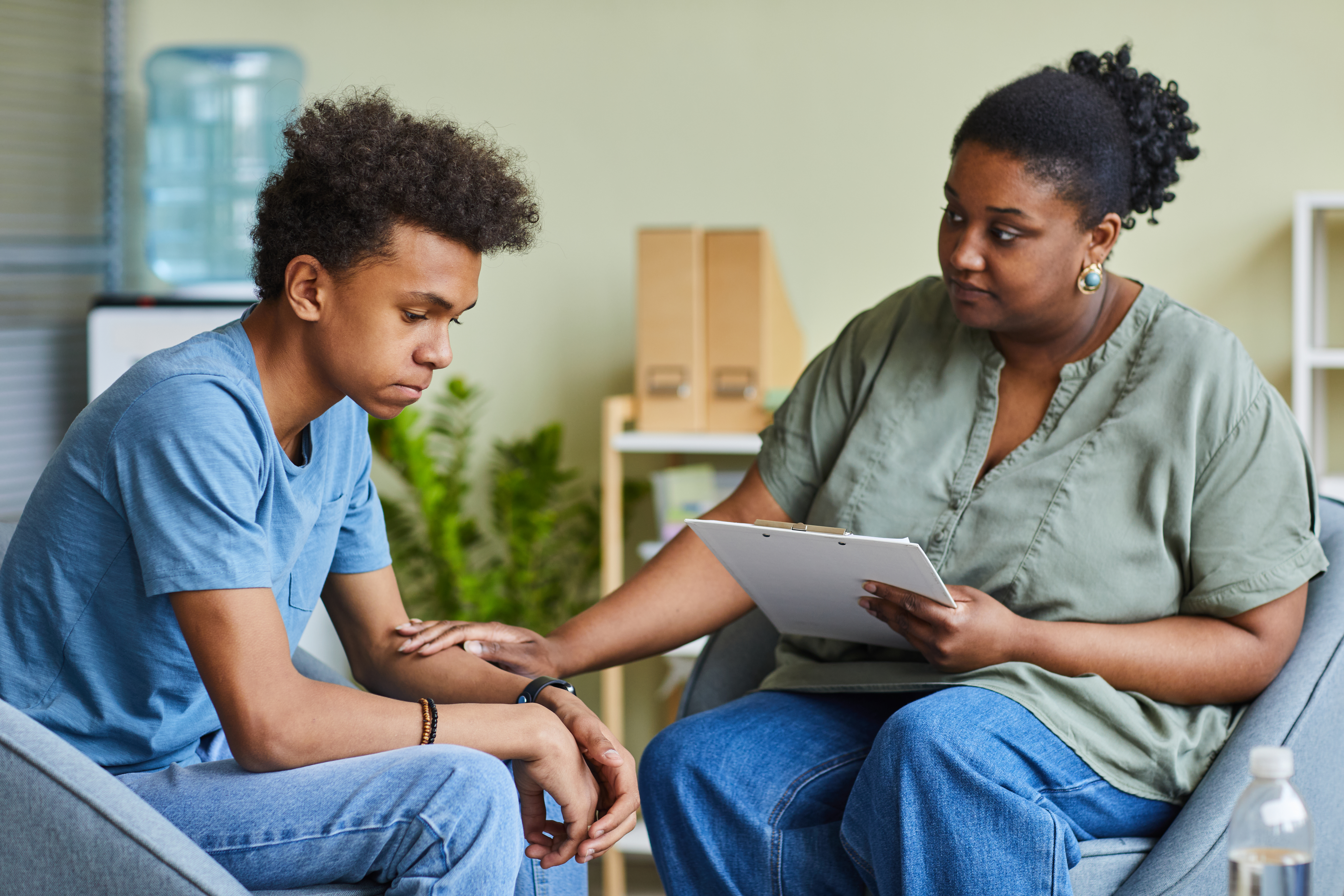 Psychologist working with teenage boy at office