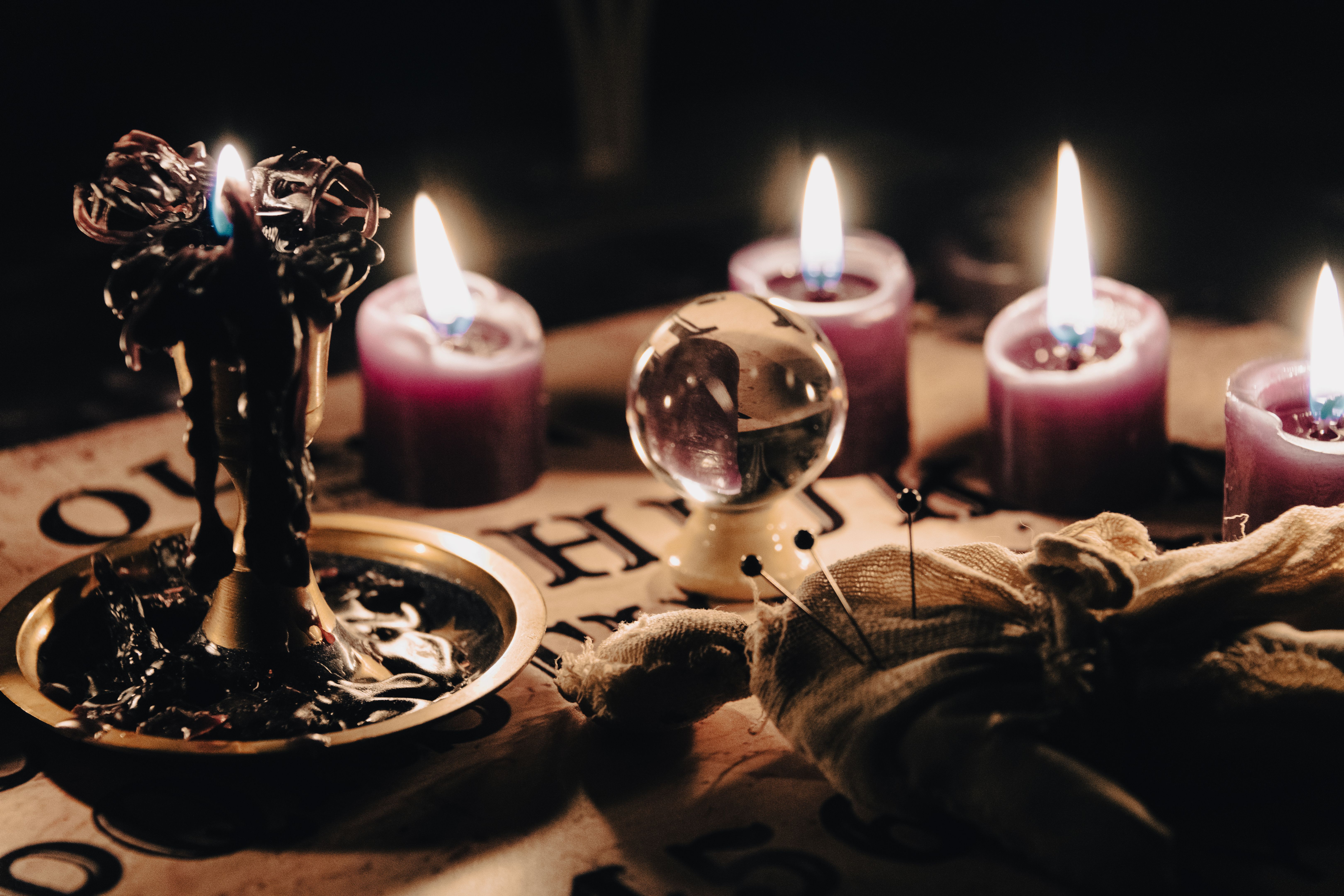 A mystical scene with a crystal ball surrounded by candles, suggesting fortune telling or a séance. A mystical scene with a crystal ball surrounded by candles, suggesting fortune telling or a séance.