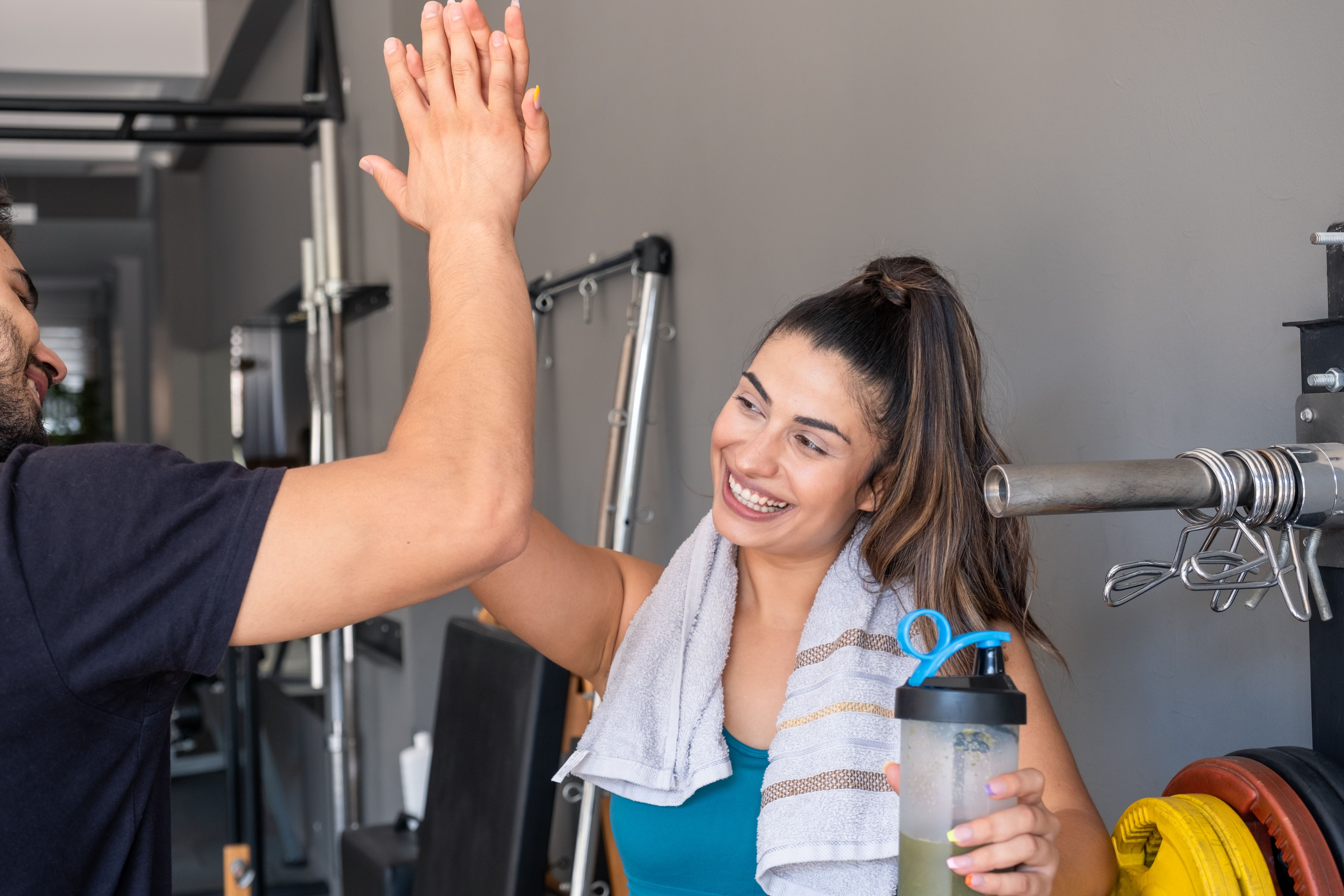 Happy athletic woman giving high five to friend at gym