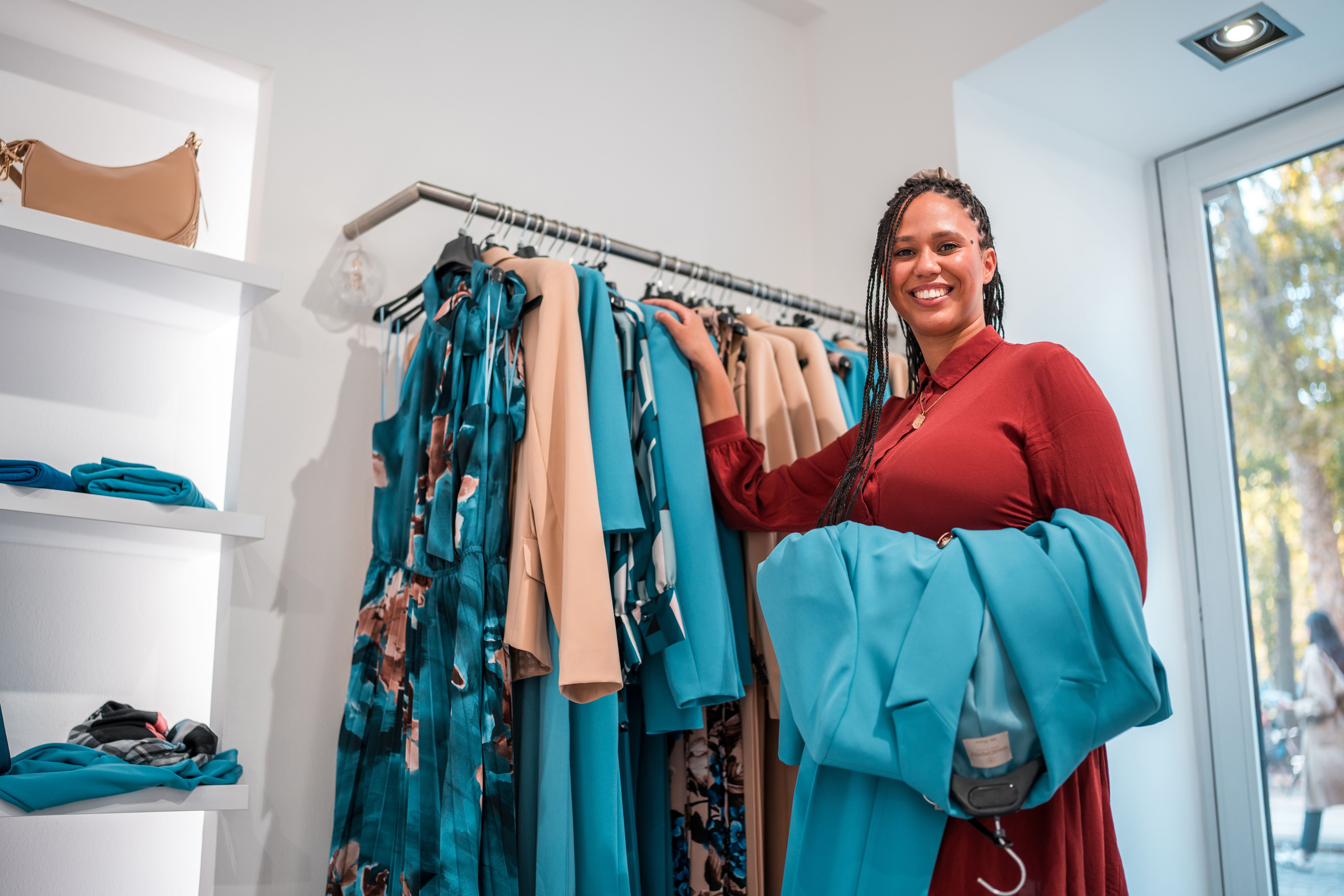 Mixed Race Female Boutique Owner Holding Clothes