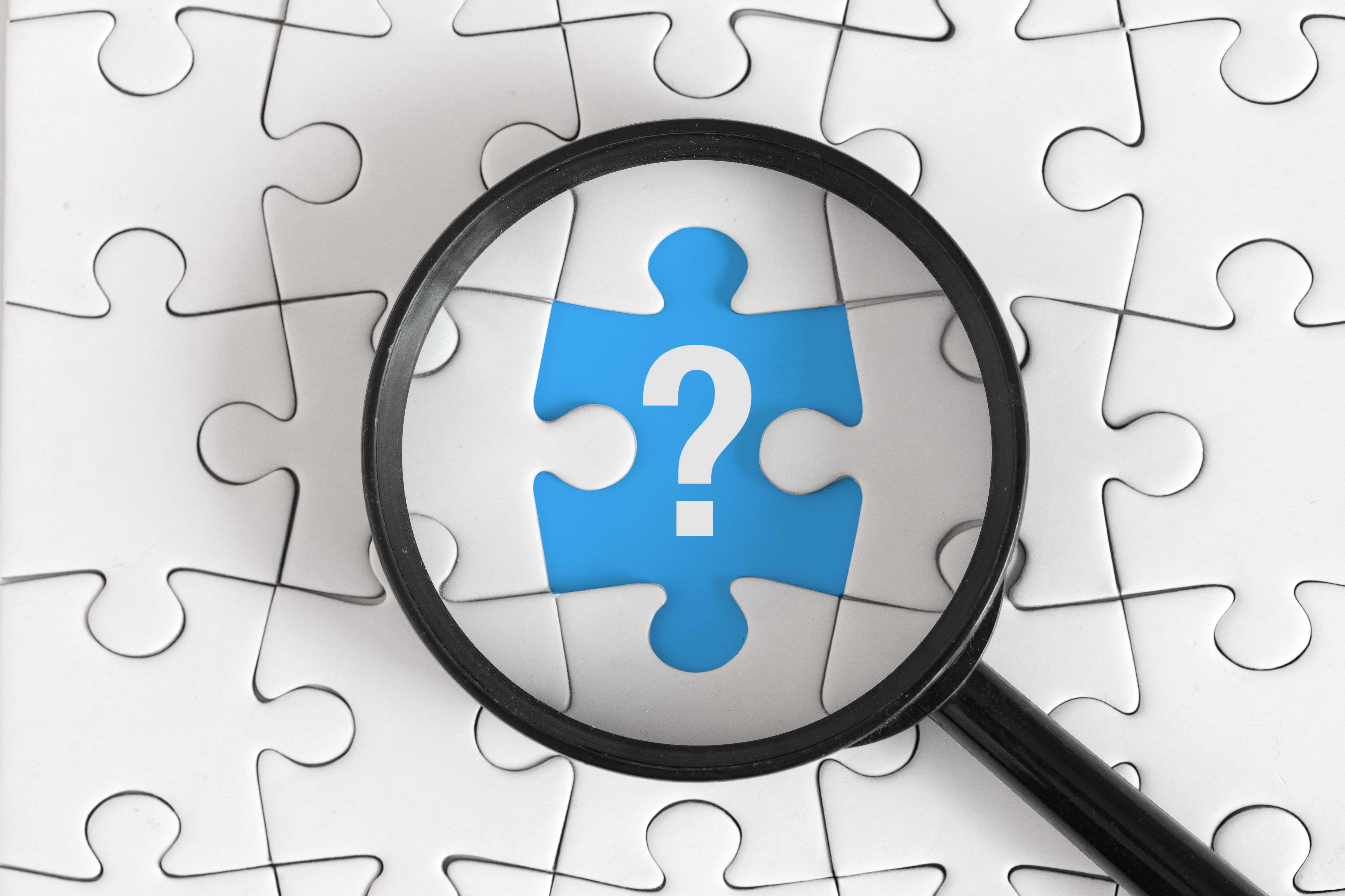 White Puzzle with Black Magnifying Glass and White Question Mark on Blue Piece, Top View