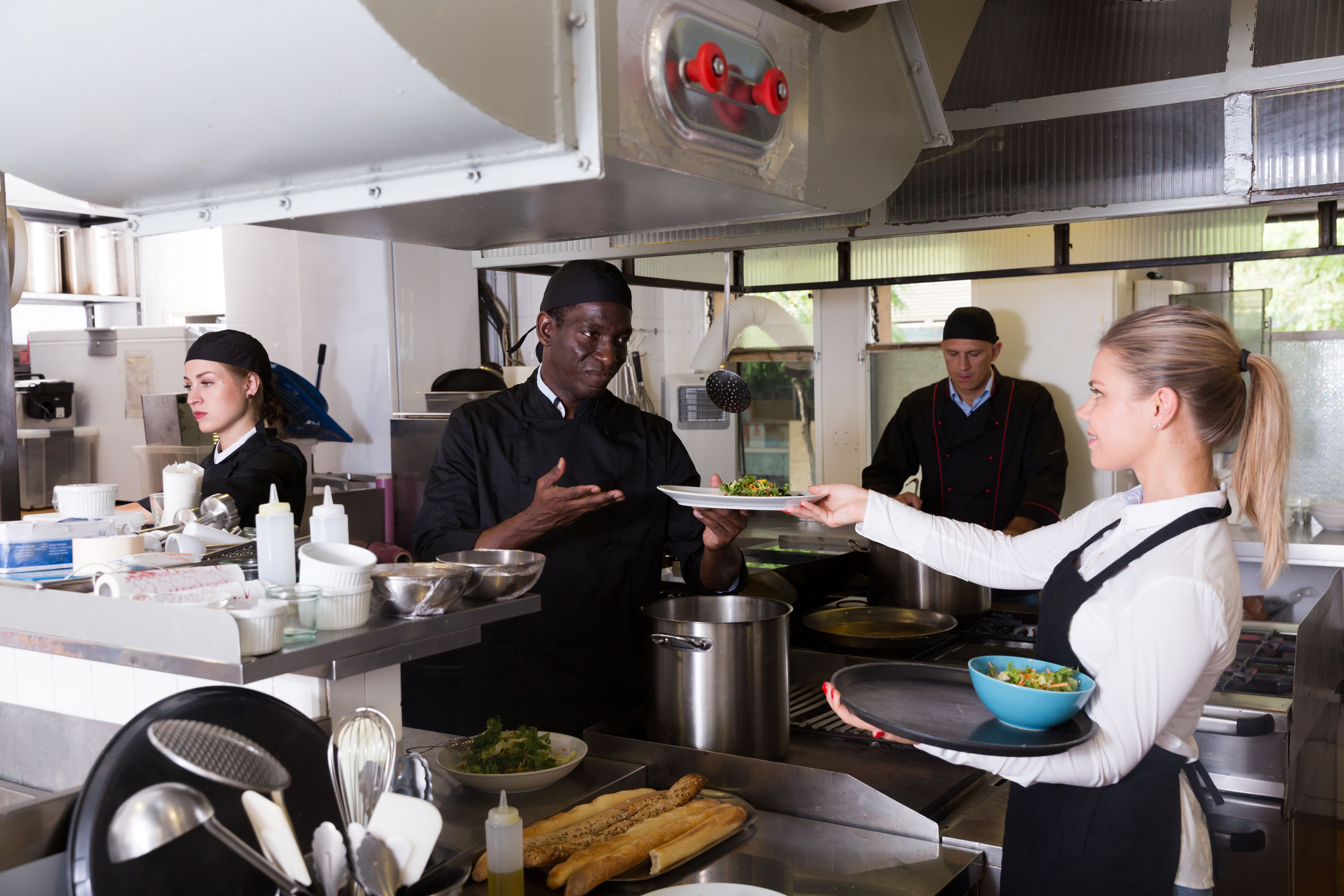 Chef afro-américain donnant le plat cuit à la serveuse