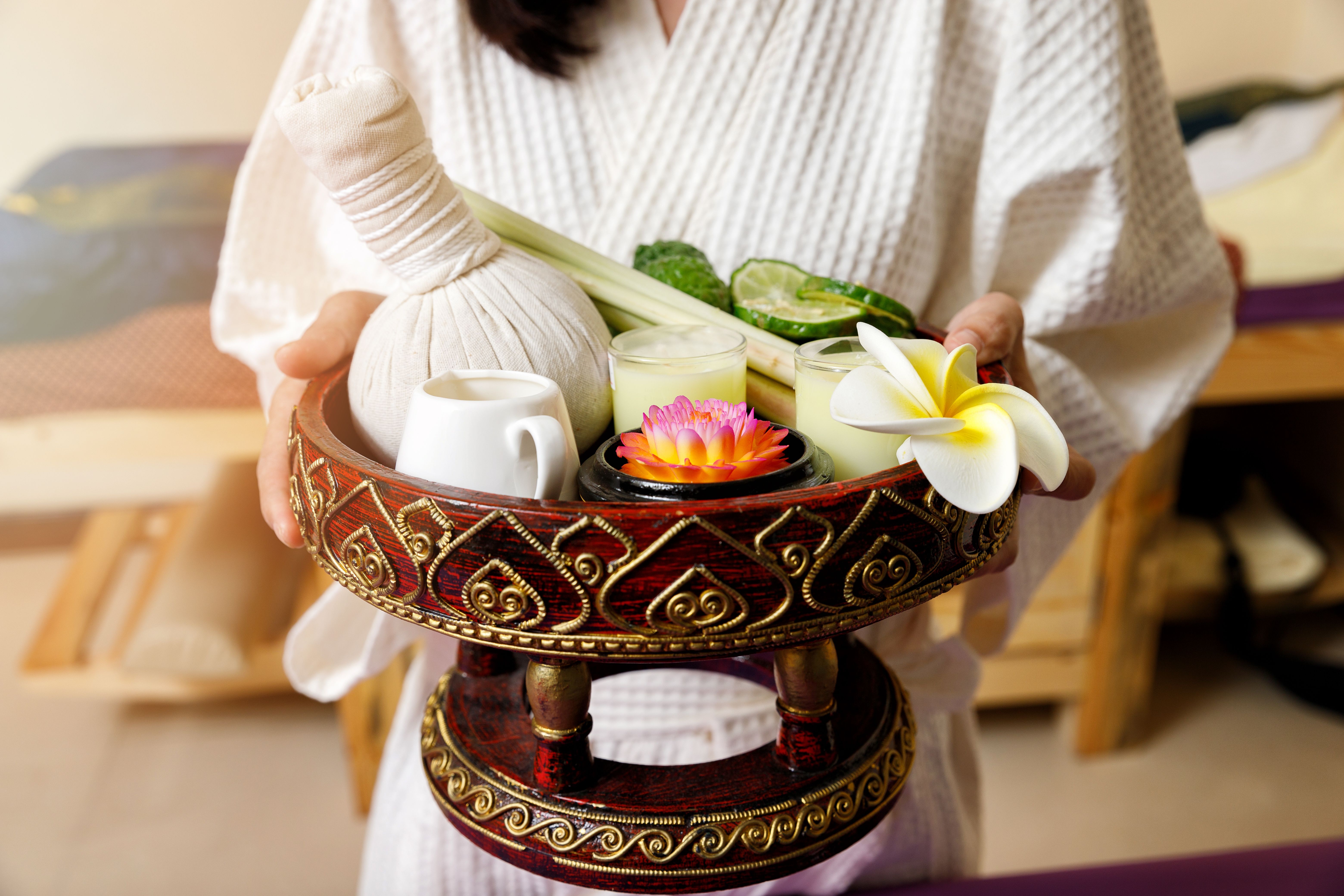 Woman holding basket of Kaffir lime or bergamot, lemongrass and other thai herbs in thai spa and massage shop.
