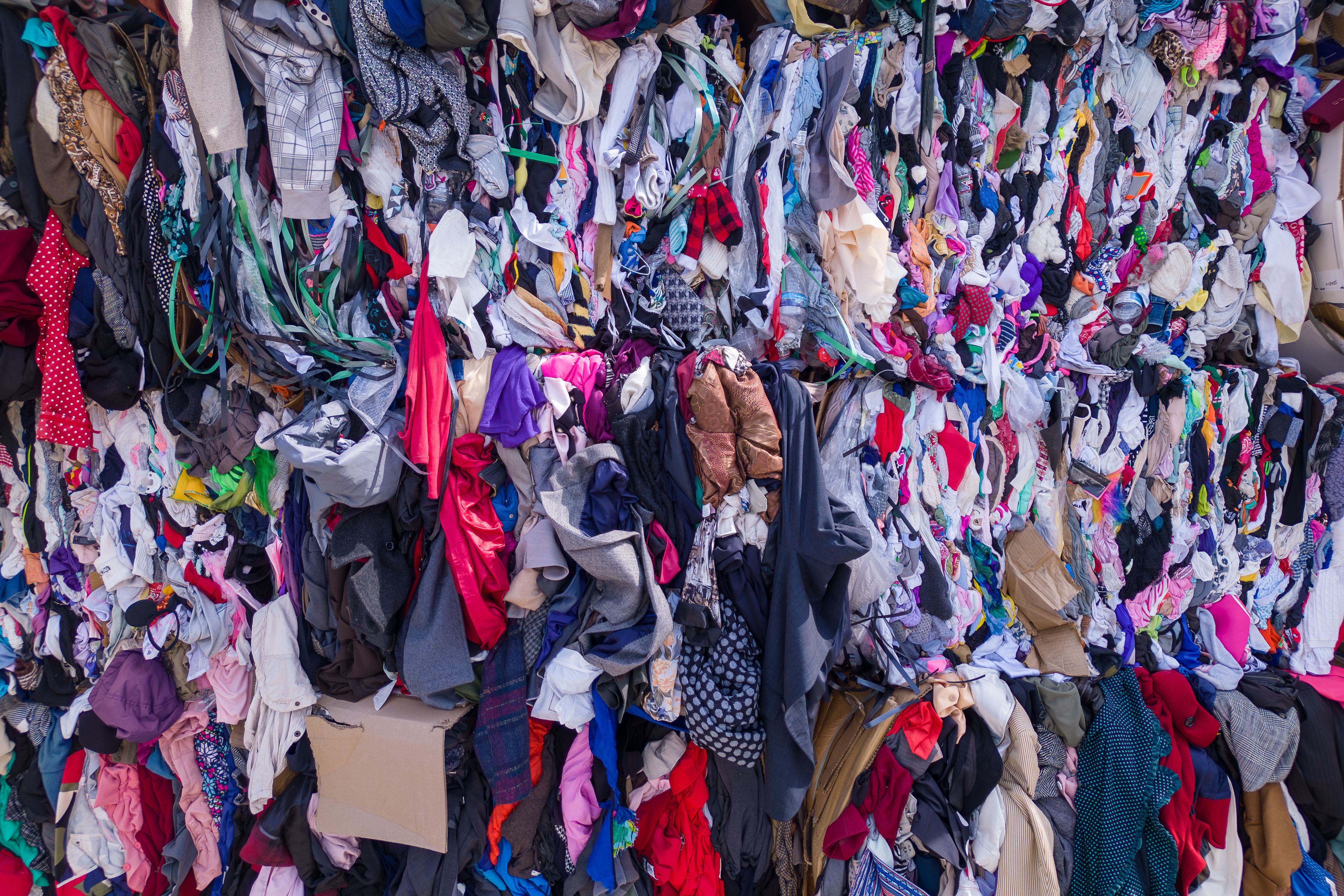 A wall of clothes with a lot of clothes on it. second hand.  clothes background. clothes recycling