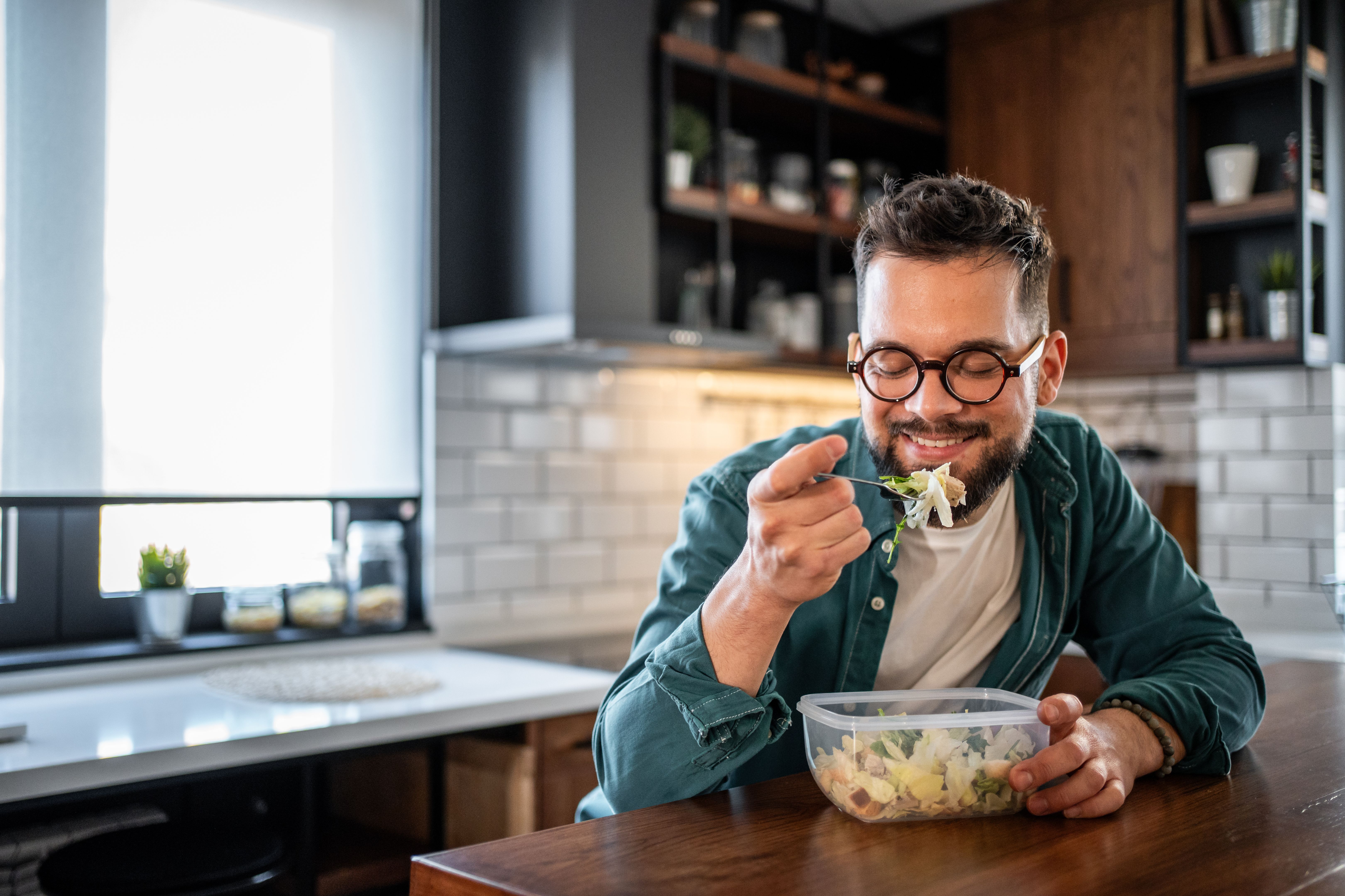 Young man enjoying a healthy salad in his modern kitchen