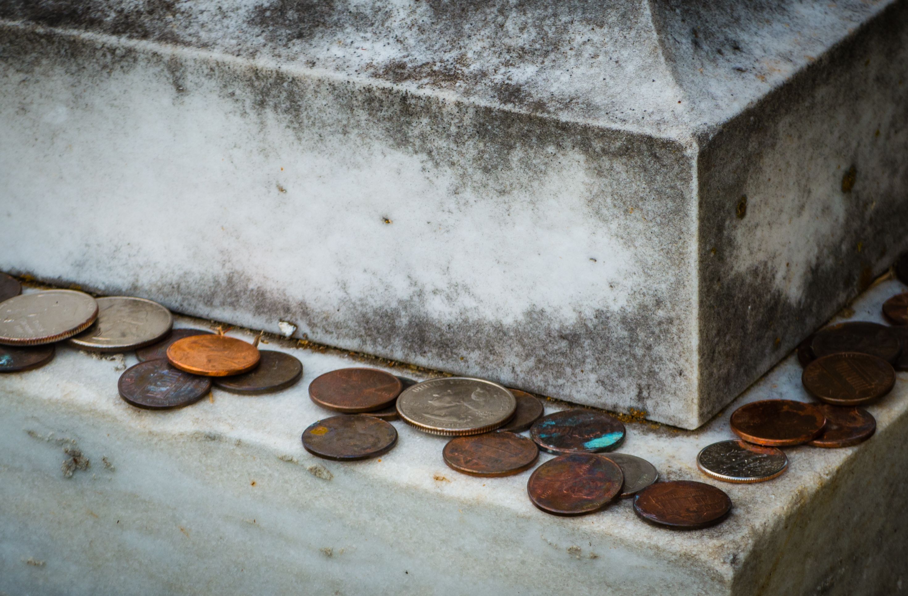 Old tradition of various american coins lying on gravestone as sign of respect Old tradition of various american coins lying on gravestone as sign of respect