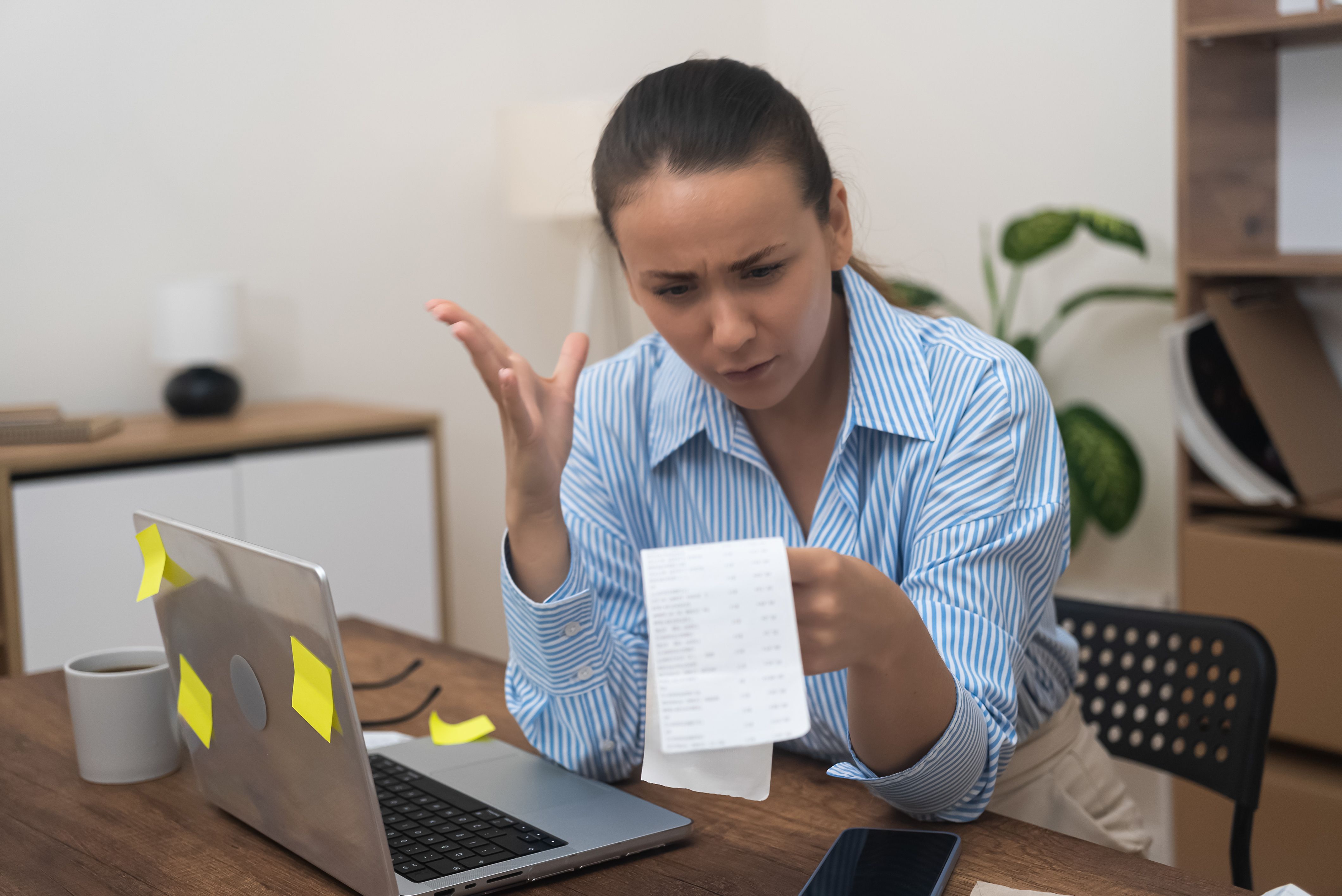 startled woman, homebound, financial stress, clutches a laptop, utility bill, and bank statements. startled woman, homebound, financial stress, clutches a laptop, utility bill, and bank statements.
