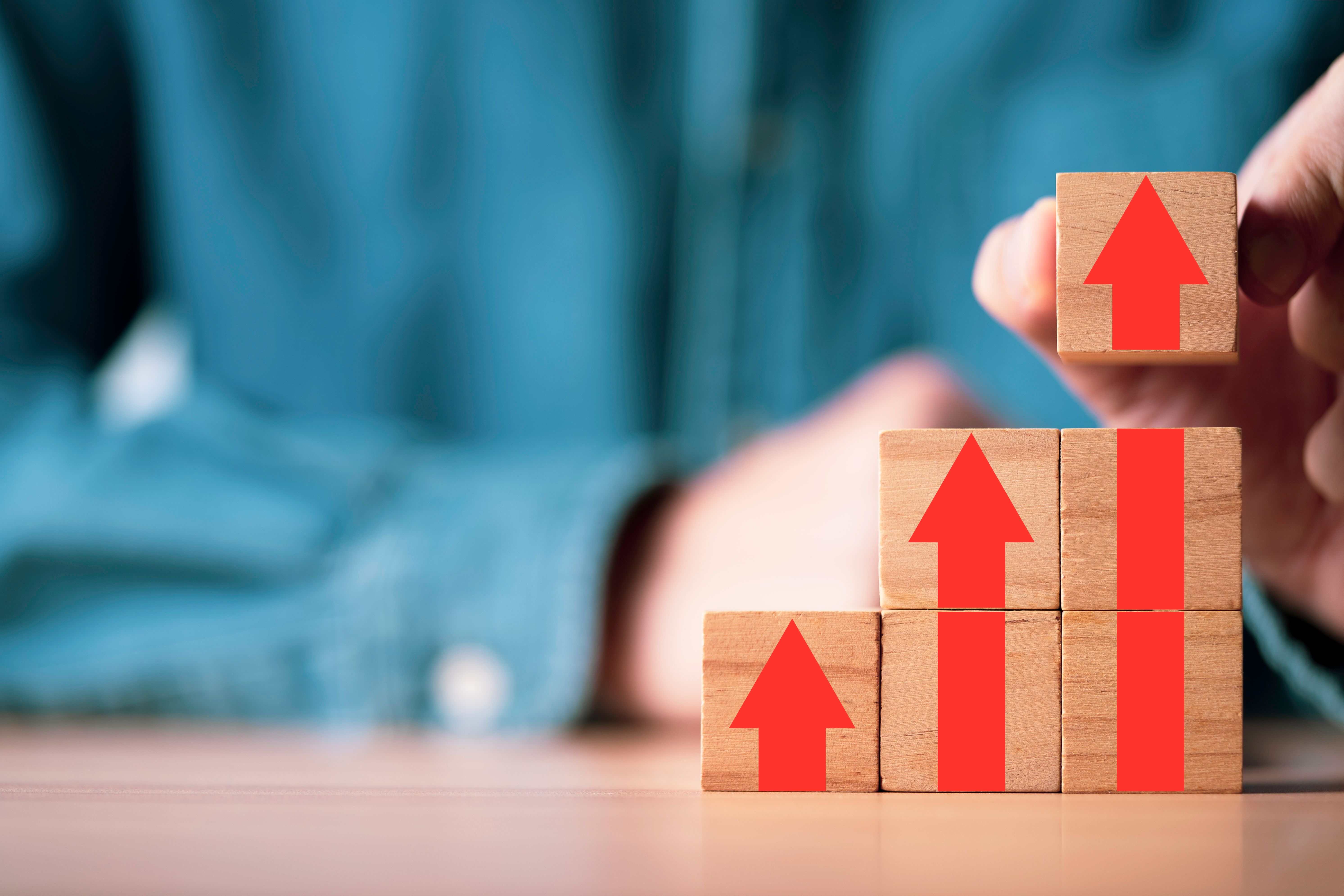 Businessman stacking red arrow on the top of wooden block for business growth and achievement success concept.