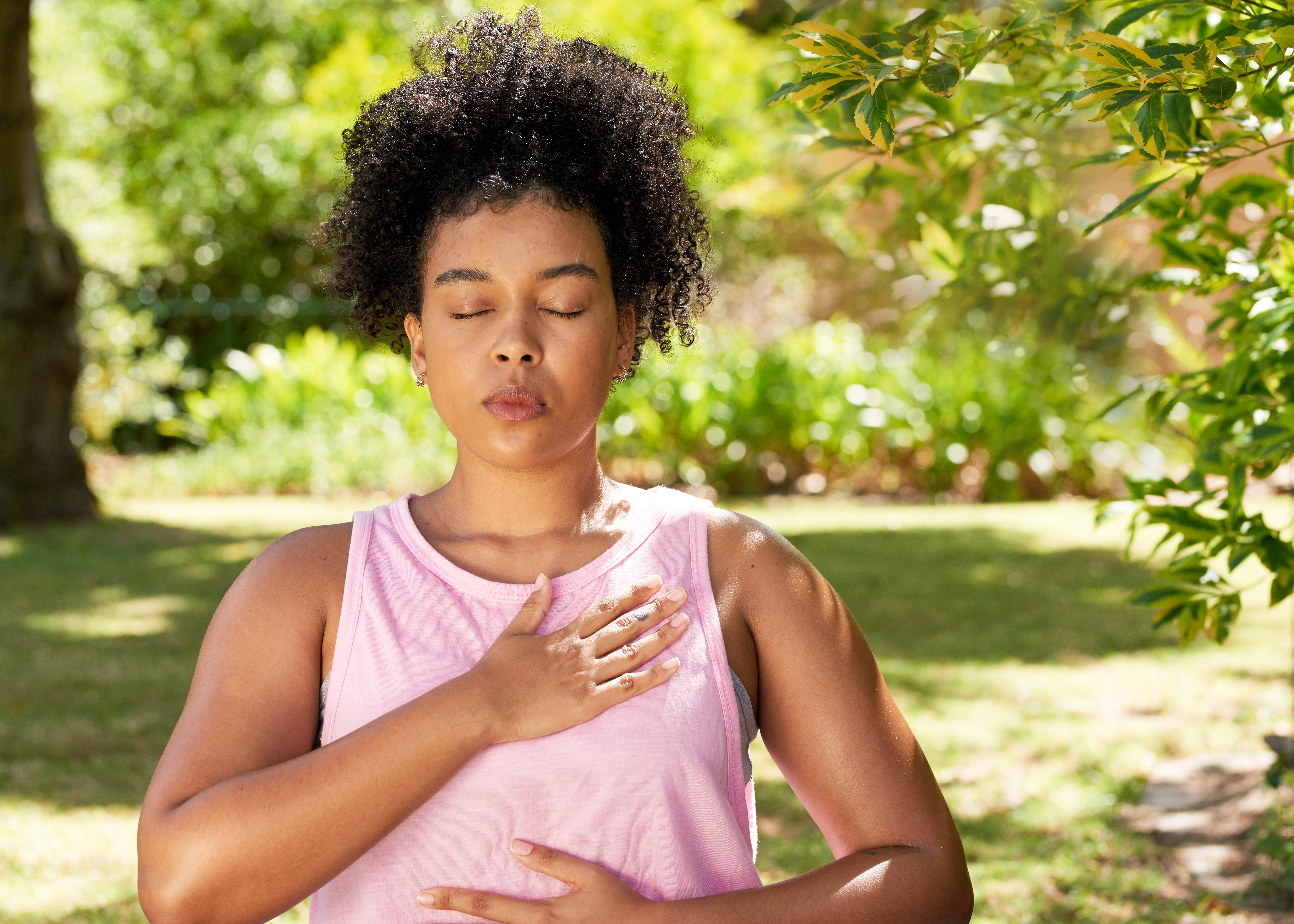 Young mutli-ethnic woman practices deep belly breathing, meditation in park